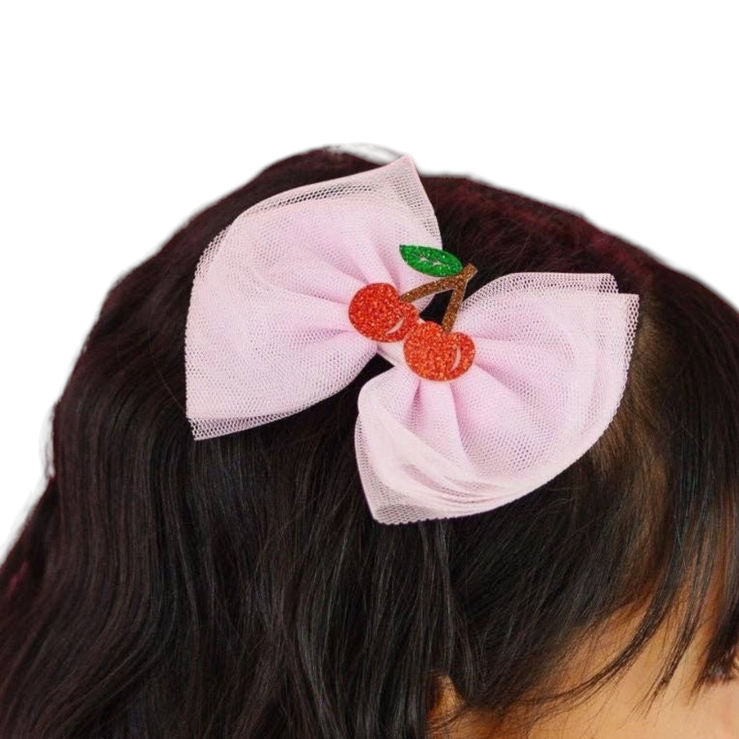 Pink hair bow with cherry decorations on a person's head against a white background