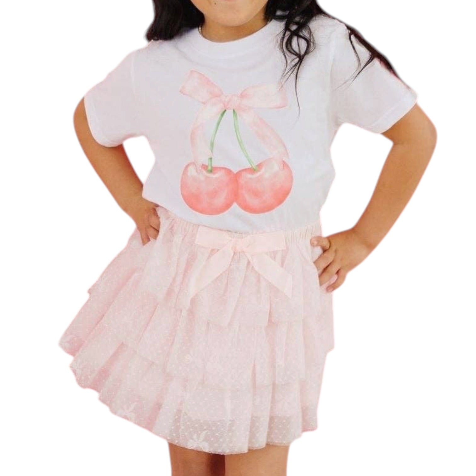 Child wearing a white t-shirt with cherry design and a pink skirt on a white background