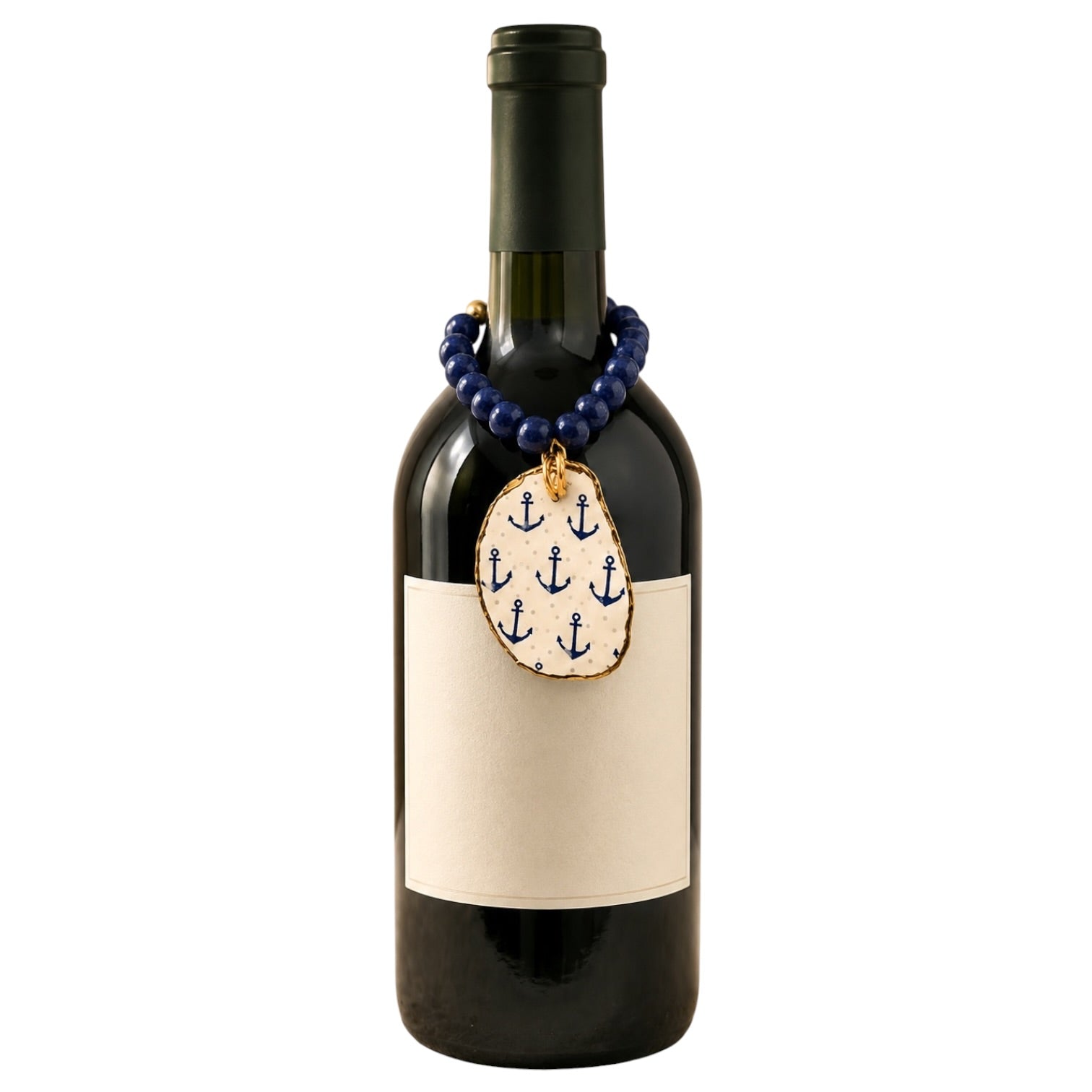 A dark glass wine bottle with a blank cream label, decorated with a blue beaded necklace and an oval anchor-patterned pendant, on a plain white background.