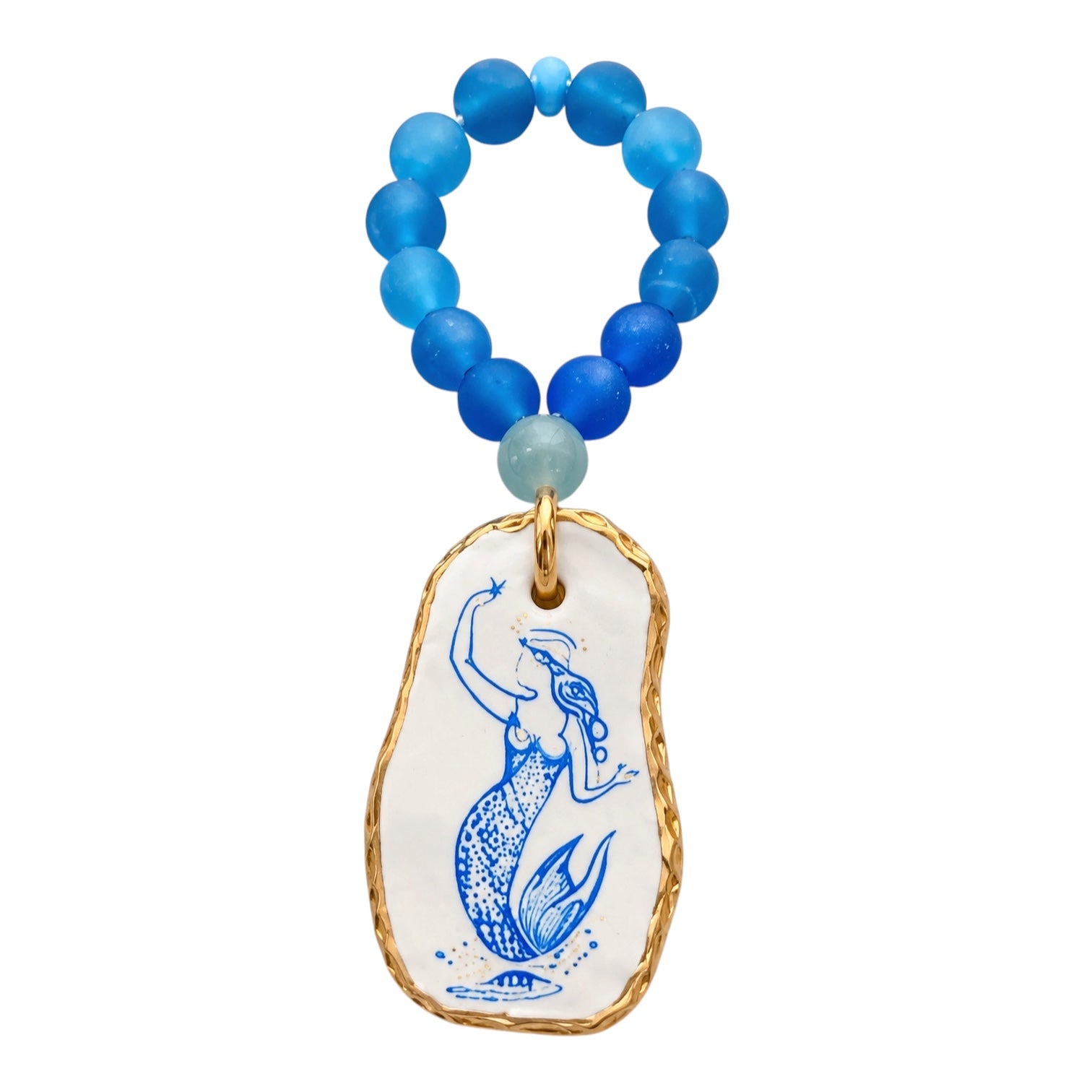 A beaded necklace with round blue beads and a dangling irregular white charm outlined in gold, featuring a blue mermaid illustration.