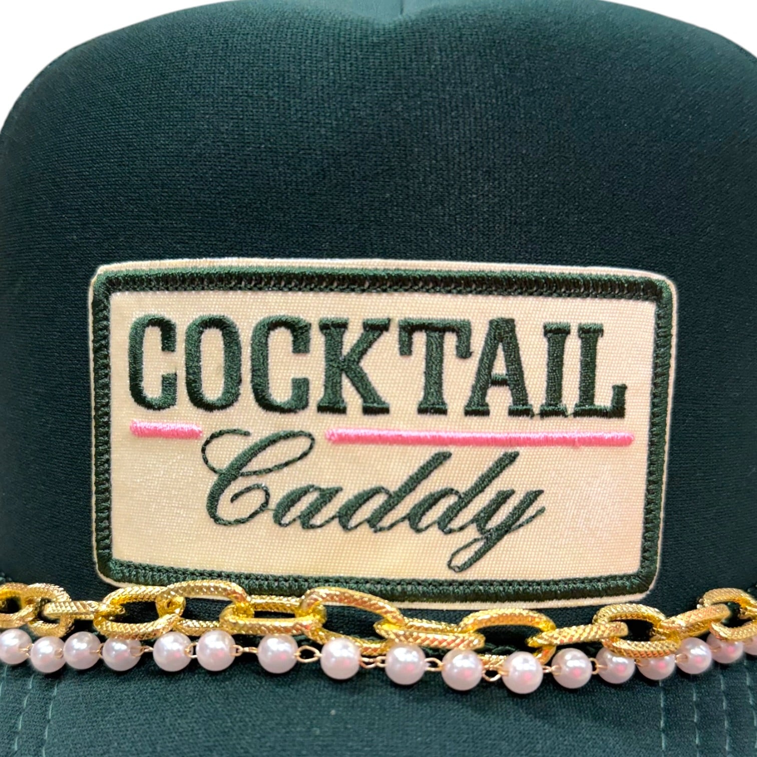 Green cap with 'Cocktail Caddy' patch and pearl embellishments on a white background