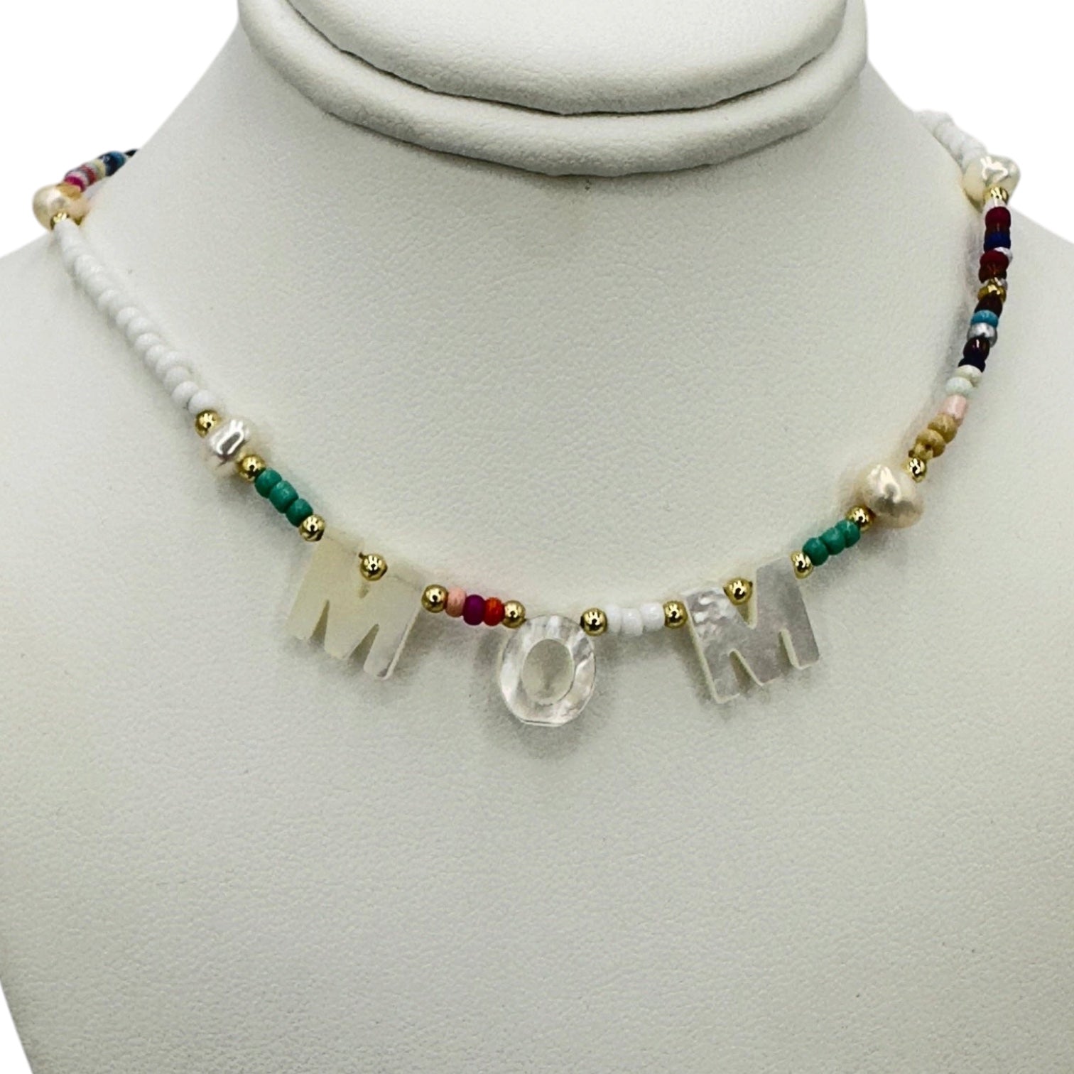 Necklace with 'MOM' letters on a mannequin bust