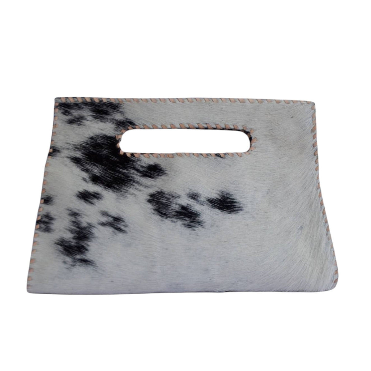 A rectangular handbag made from cowhide with a black and white spotted pattern, featuring a cutout handle and light-colored contrast stitching, shown against a plain white background.
