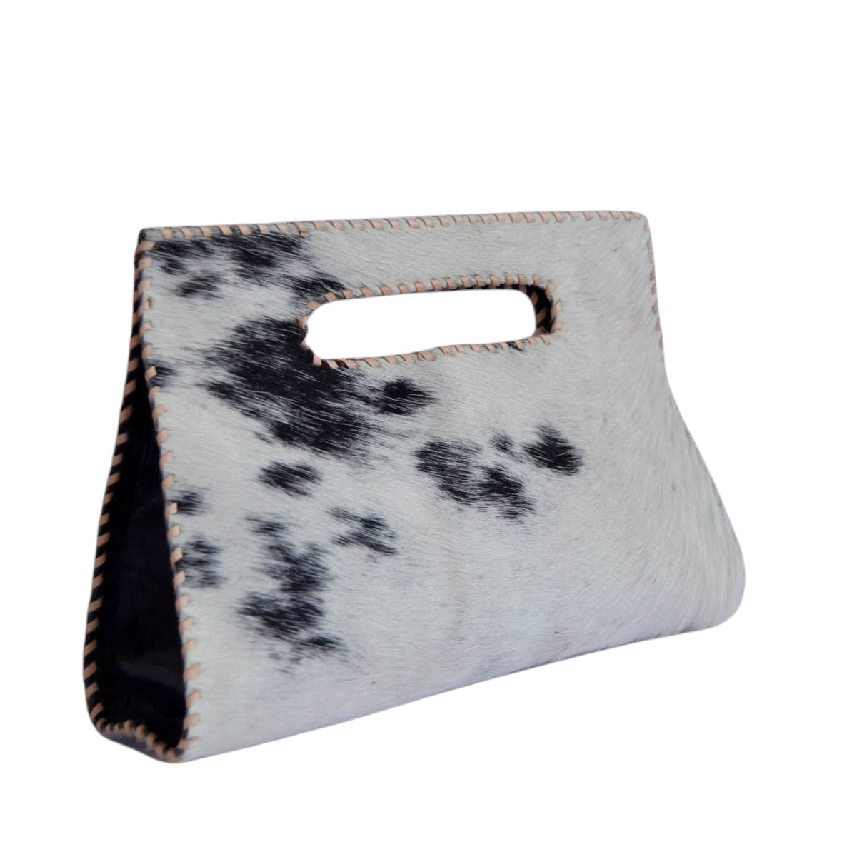 A small handbag made from black-and-white spotted cowhide with a cutout handle, shown on a plain white background.