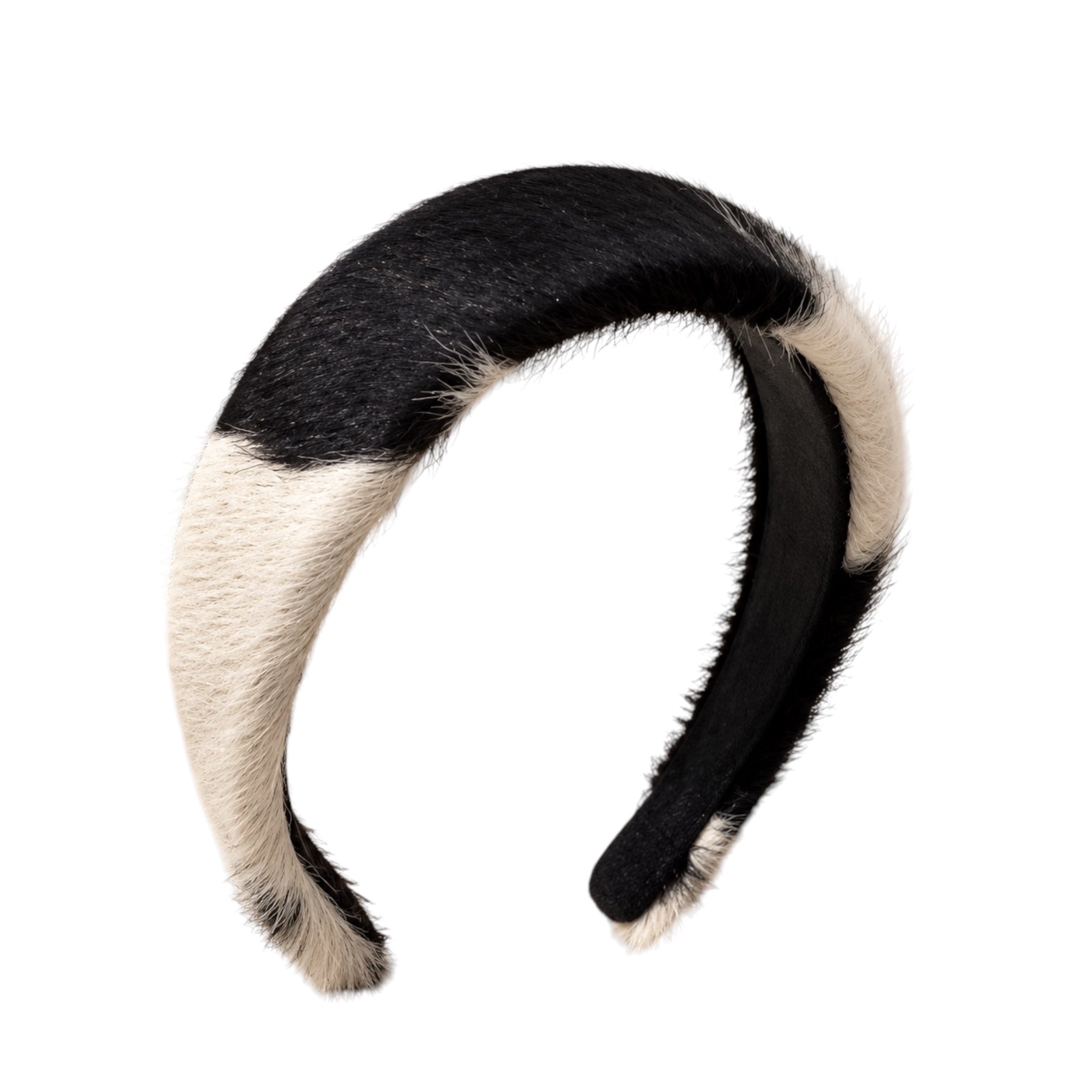 A curved faux fur headband with a black and cream color-blocked pattern, shown against a plain white background.
