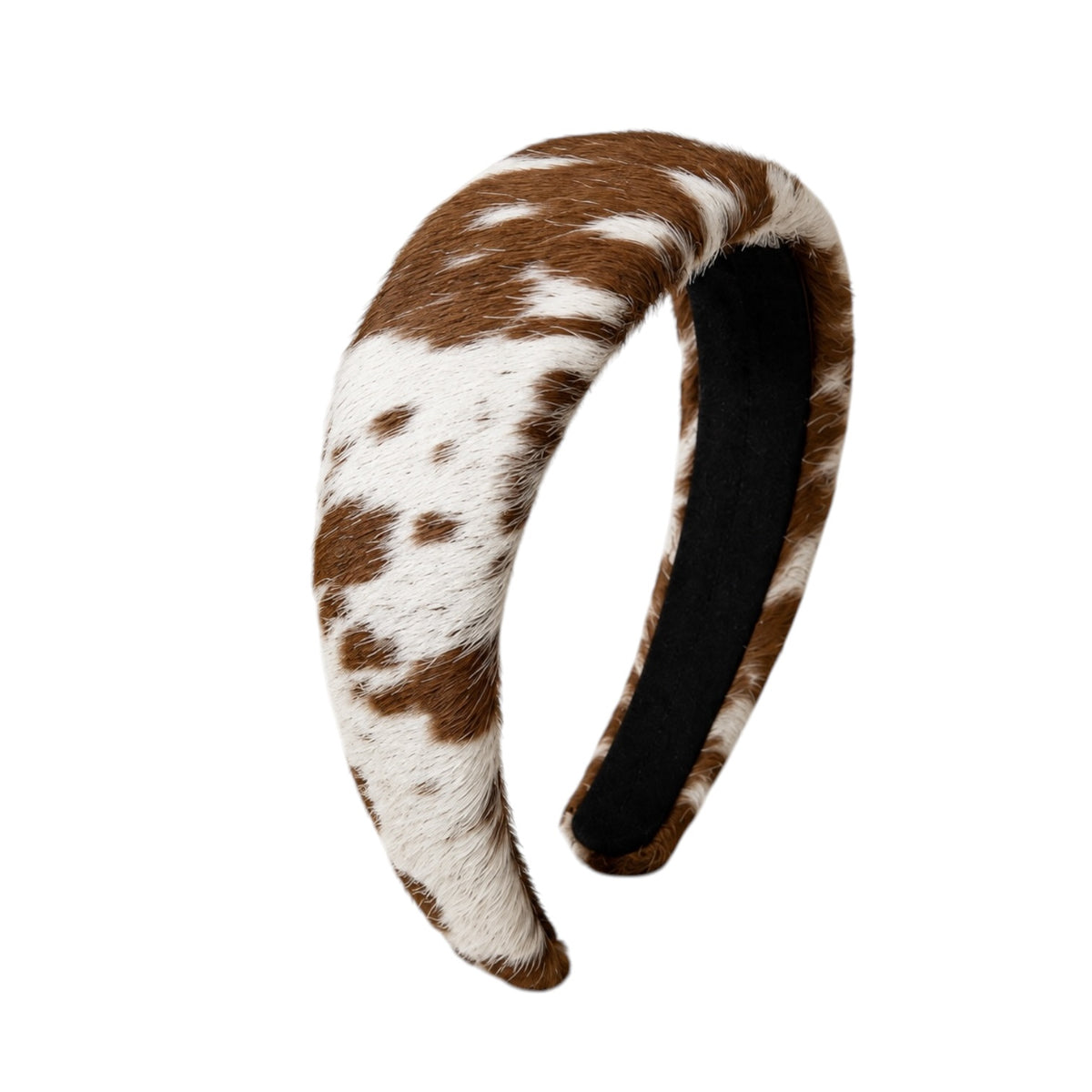 A curved headband featuring a brown and white cowhide pattern on the exterior, with a black fabric lining visible on the inner side, set against a plain white background.