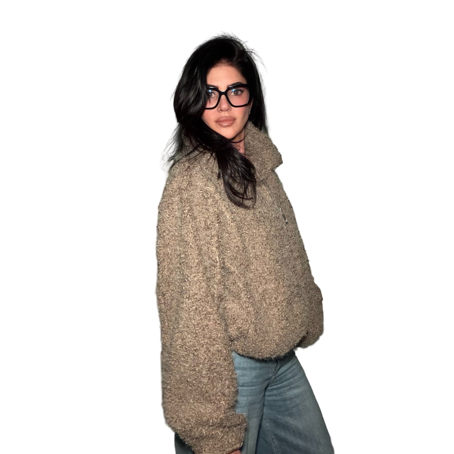 Person wearing a beige sweater and glasses against a plain wall