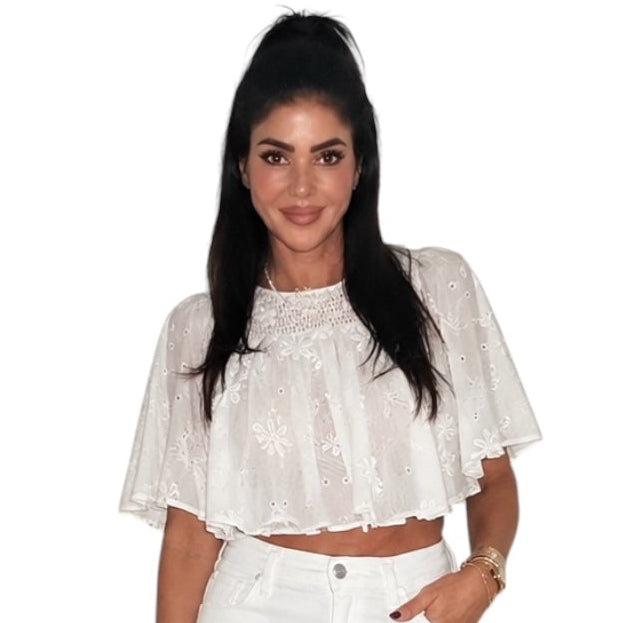 a woman wearing a cream embroidered top with white jeans
