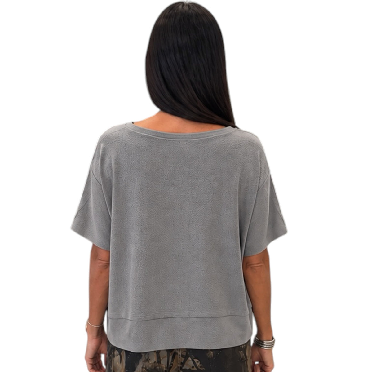 A woman viewed from the back wearing a short-sleeve, loose-fit gray top, shown against a plain white background.