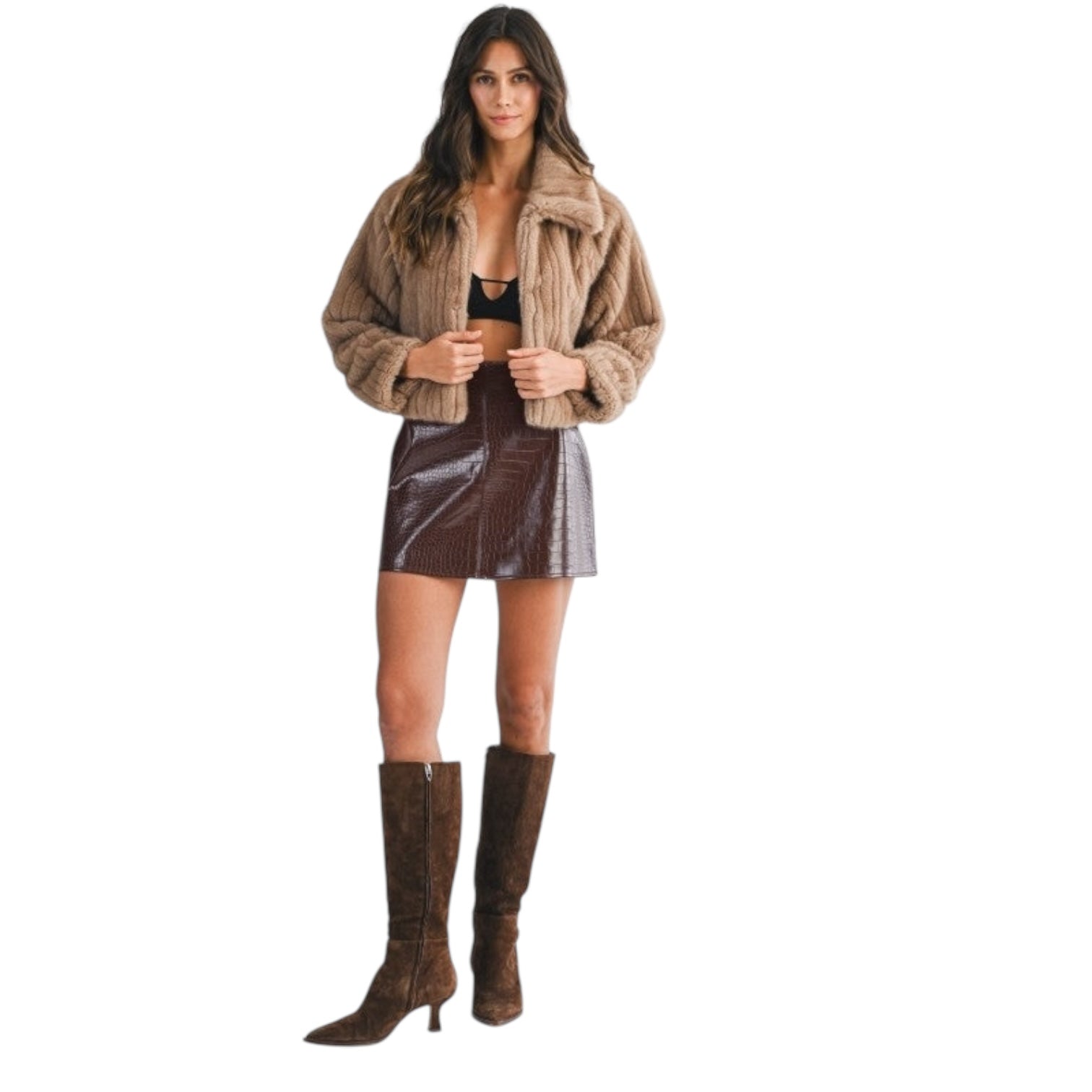 Woman wearing a brown jacket, black top, and brown skirt with knee-high boots on a white background