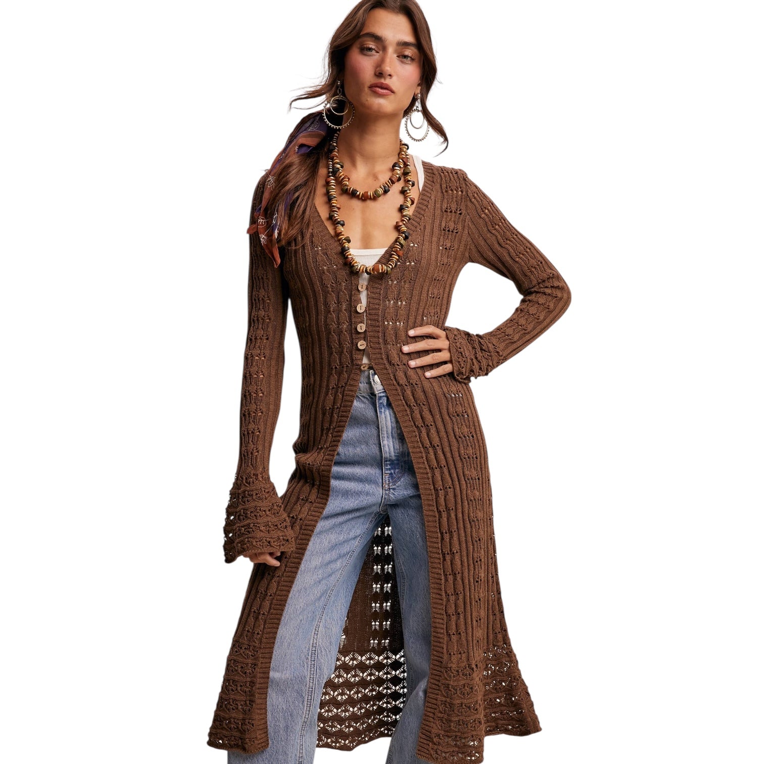 Woman wearing a brown ribbed cardigan over a denim dress with a white background