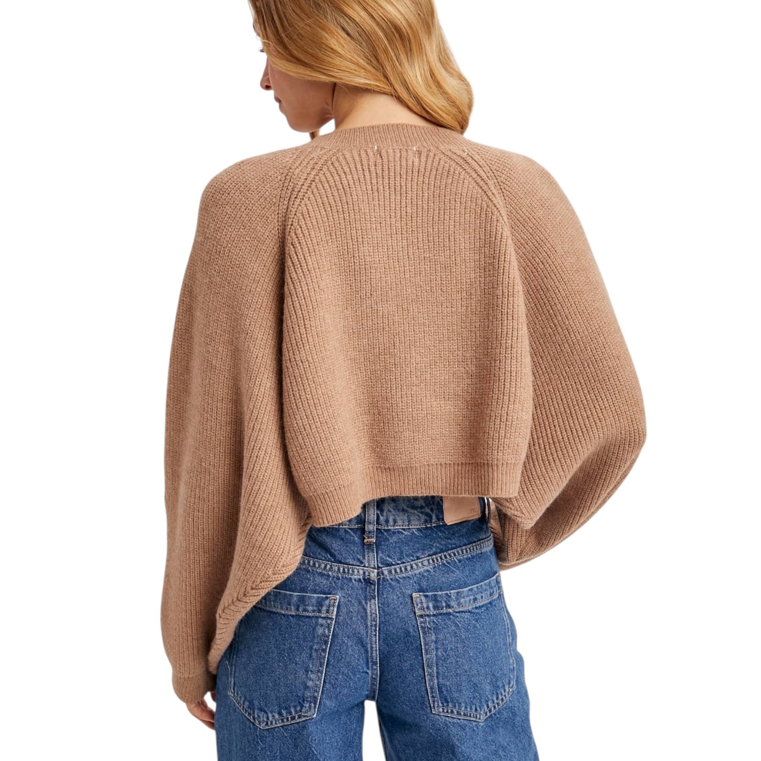Person wearing a beige sweater and blue jeans on a white background