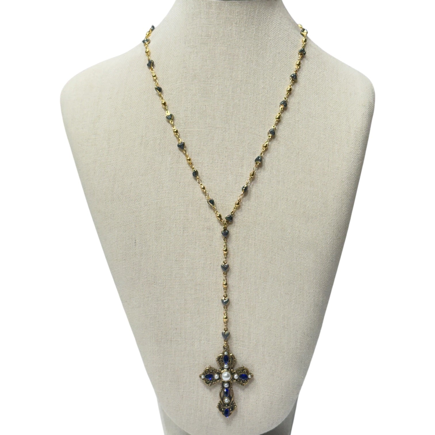 A long gold-tone lariat-style necklace with dark blue and white gemstone accents, displayed on a beige fabric jewelry bust against a white background.