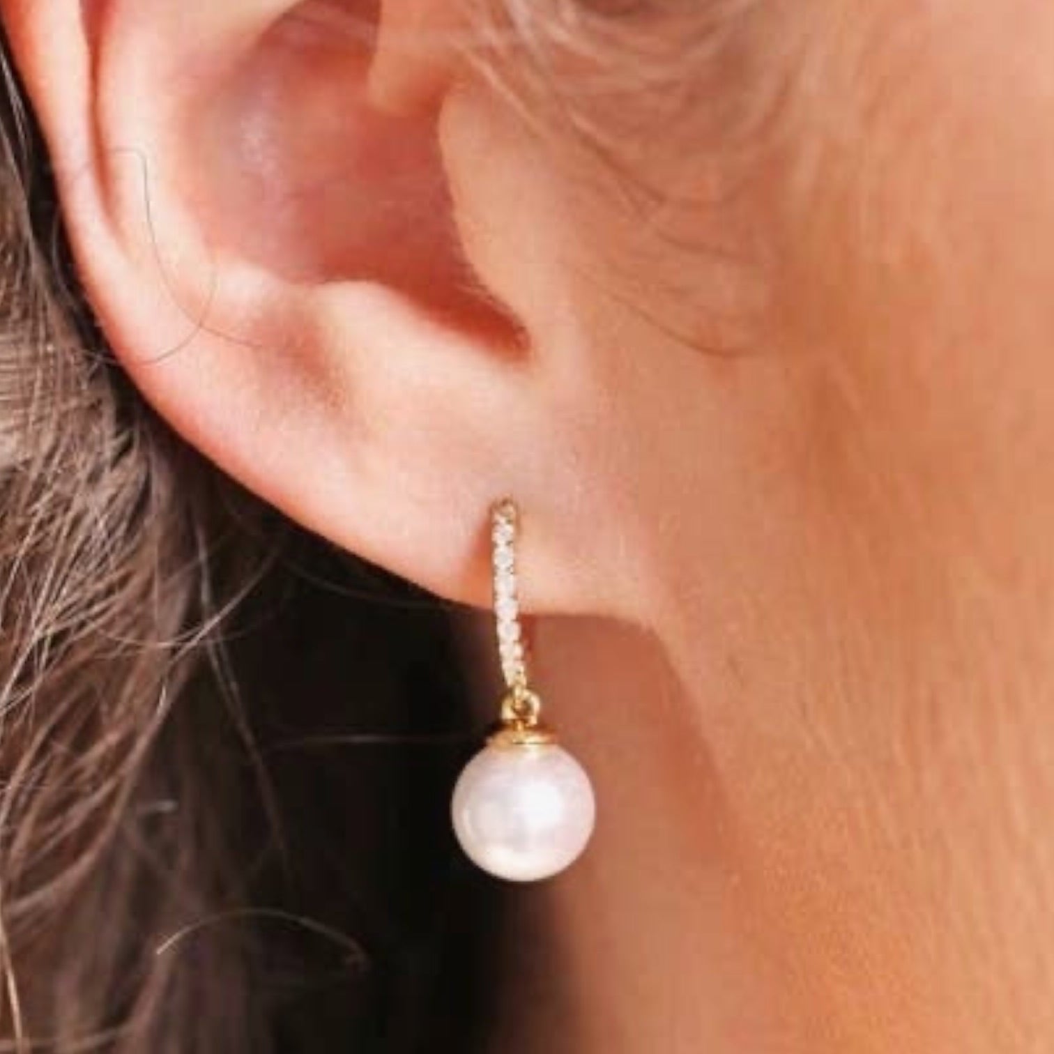 Pearl earring worn on an ear with a blurred background