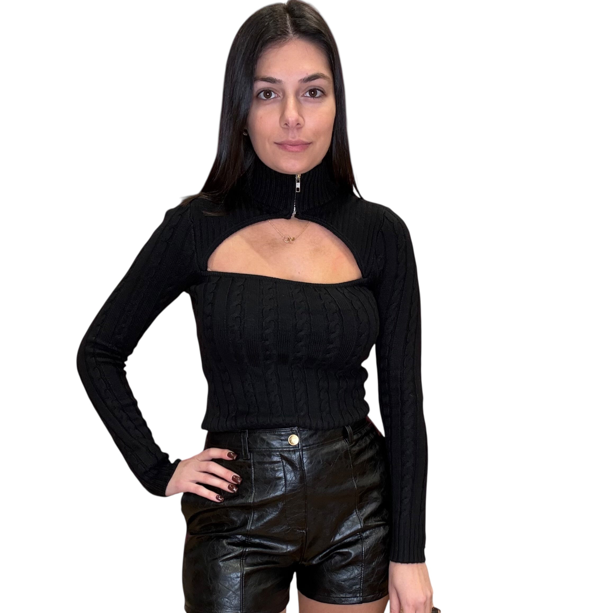 Woman wearing a black long-sleeve top with cut-out design and black leather shorts on a white background