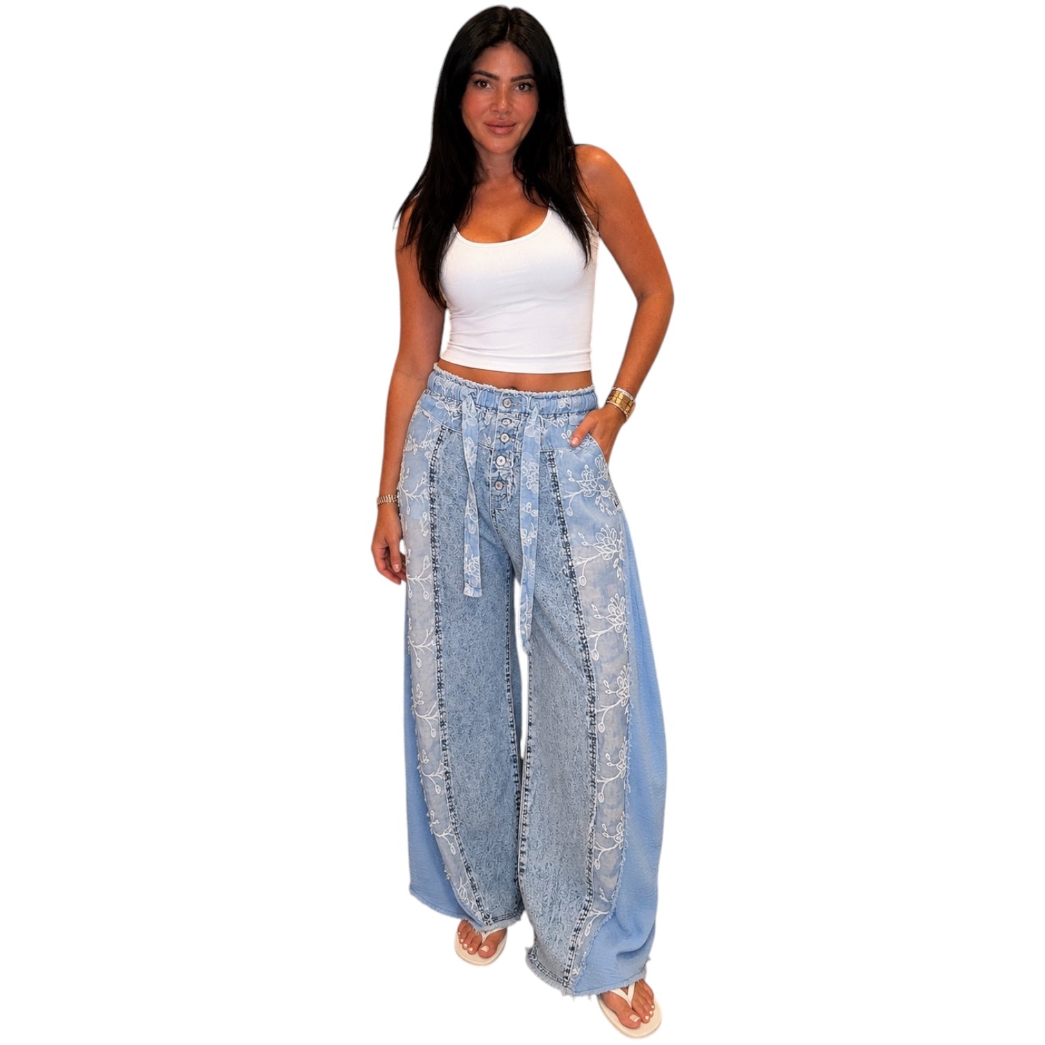 Woman wearing a white top and light blue wide-leg jeans on a white background