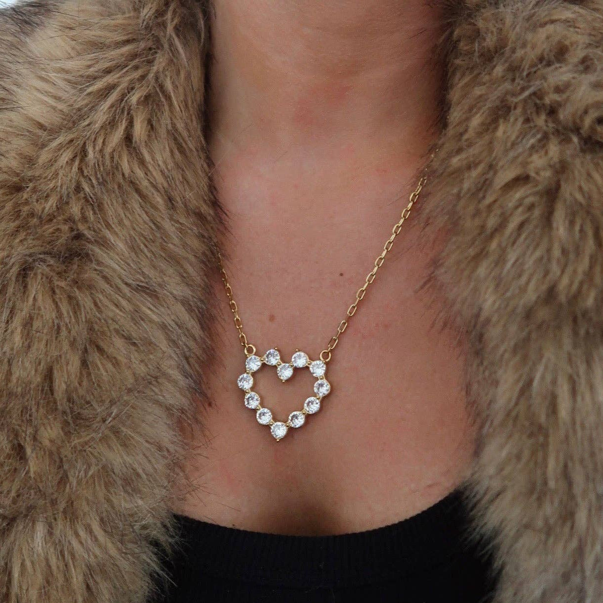 Heart-shaped diamond necklace worn by a person in a fur coat