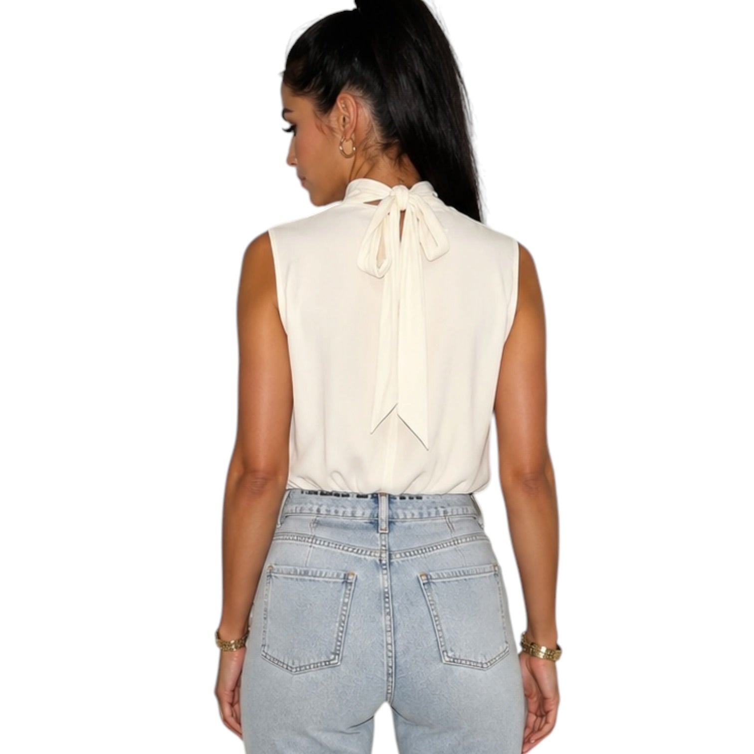 A woman shown from the back wearing a sleeveless cream-colored blouse with a large bow at the back of the neck, paired with light-wash blue jeans, against a plain white background.