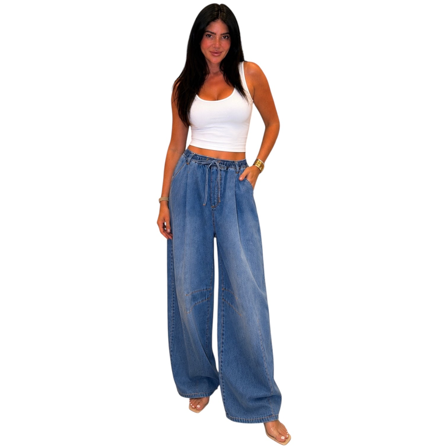 Woman wearing a white top and blue wide-leg jeans on a white background