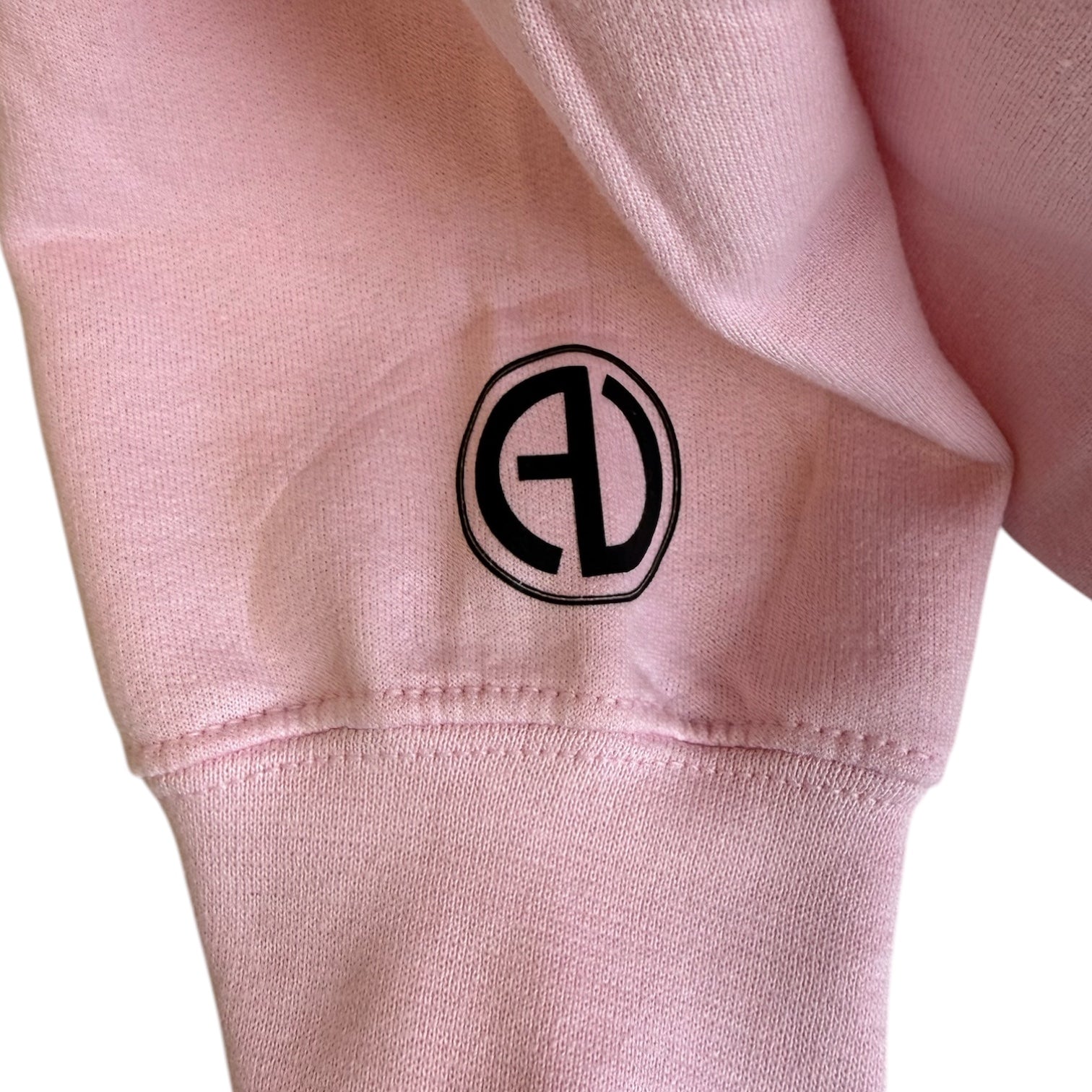 Close-up of a pink sweatshirt with a black logo on a white background