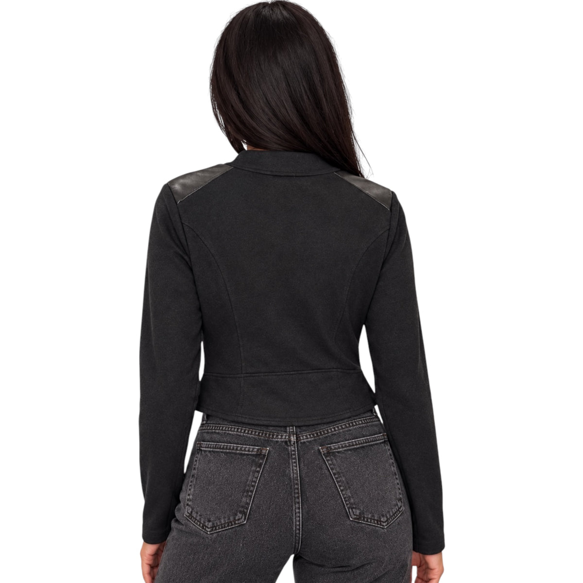 A woman viewed from the back wearing a black cropped long-sleeve jacket with dark gray shoulder panels and dark gray jeans, set against a plain white background.