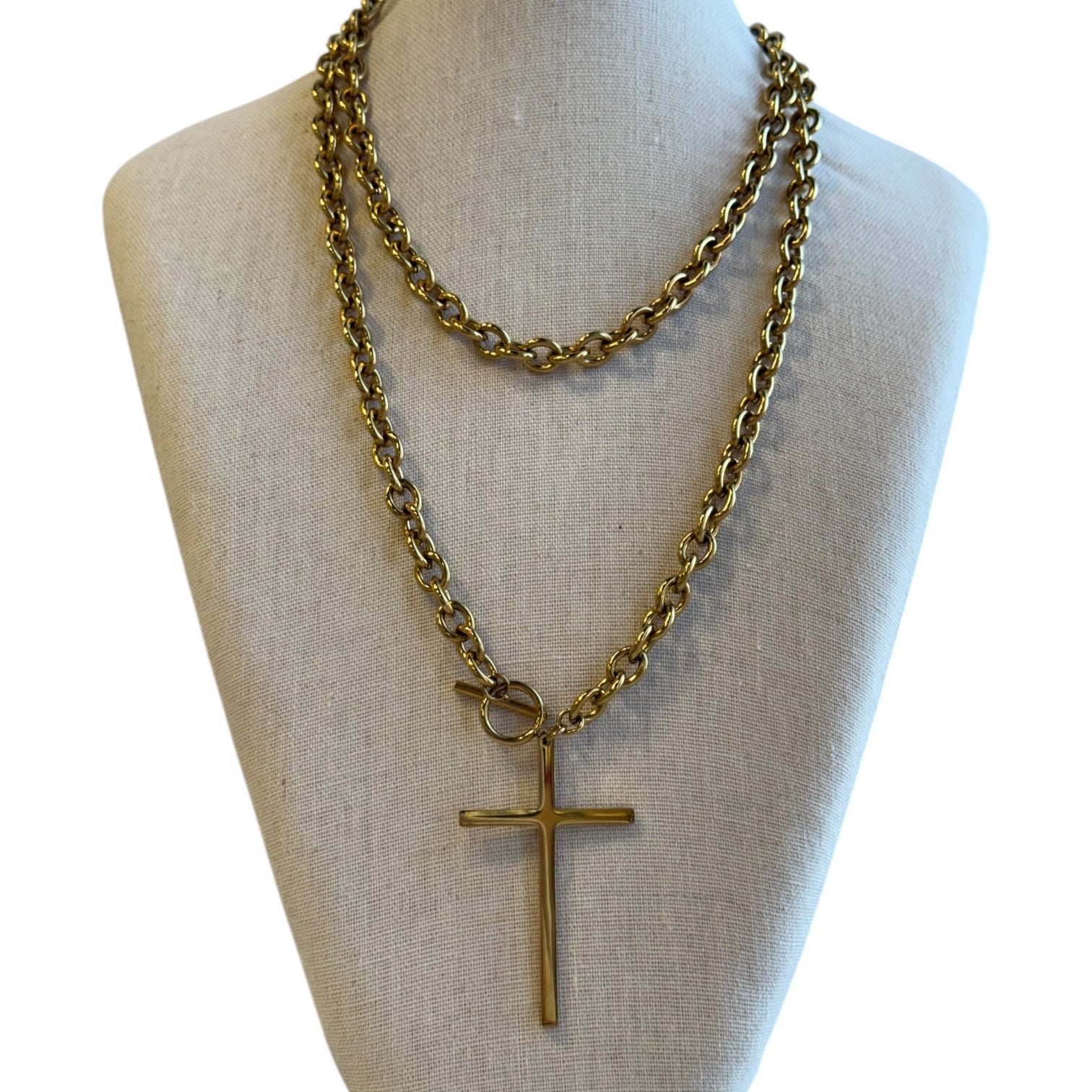 Gold chain necklace with a cross pendant on a mannequin bust.