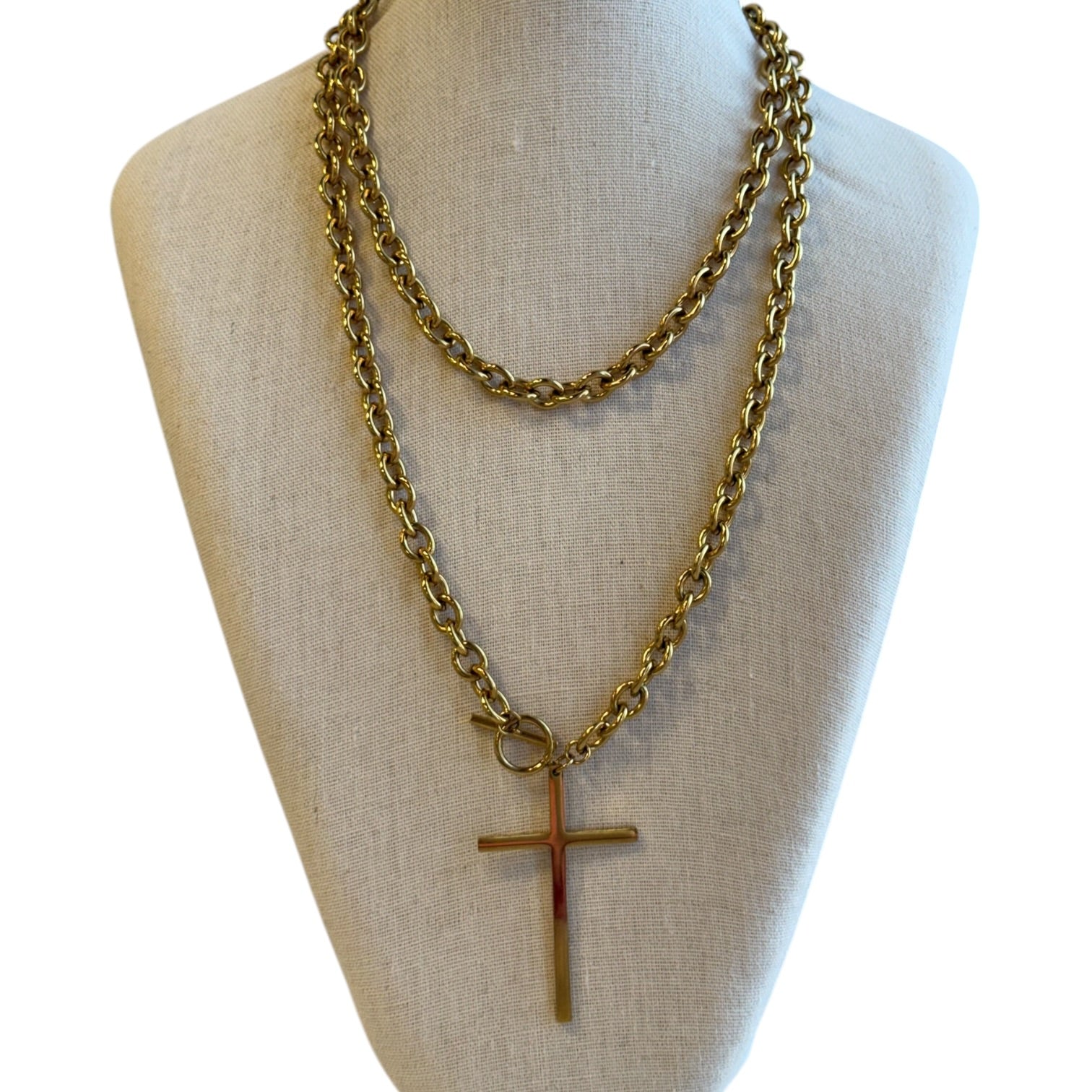 Gold chain necklace with a cross pendant on a mannequin bust.