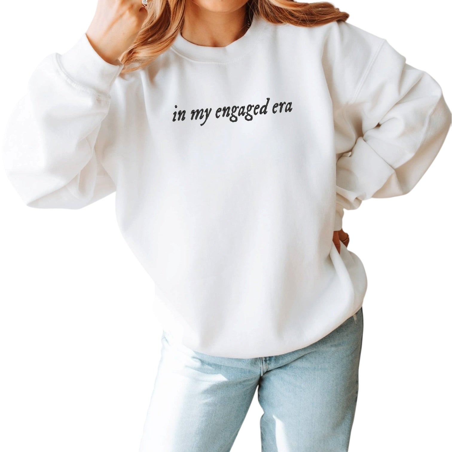 White sweatshirt with 'in my engaged era' text worn by a person on a white background