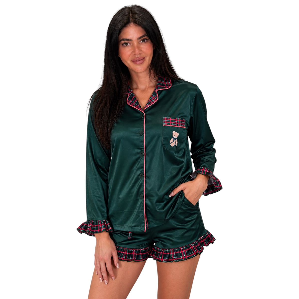 A woman modeling a dark green satin pajama set with red and blue plaid trim, featuring a long-sleeve button-front top with a pocket and matching shorts.