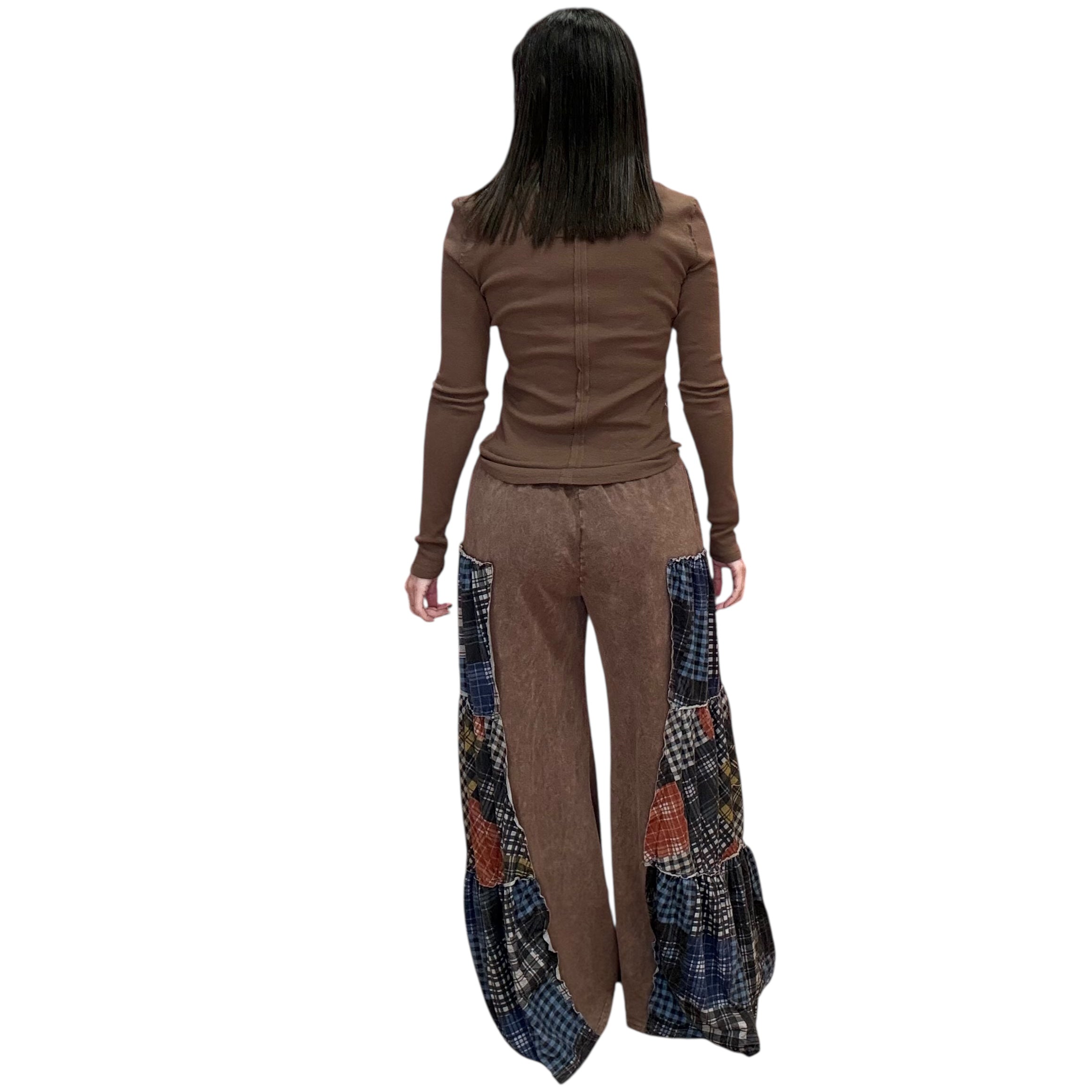 Woman wearing a brown top and patchwork pants on a white background