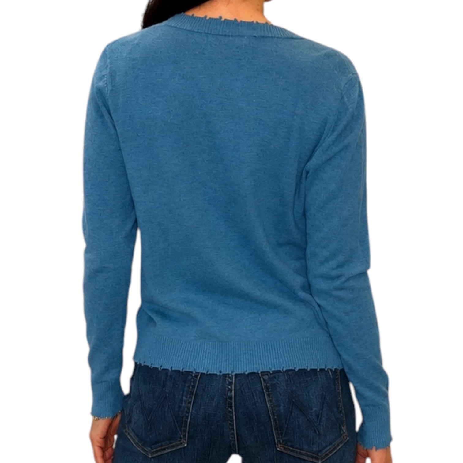 A person shown from the back wearing a blue long-sleeve knit sweater with a raw, frayed hem and neckline, paired with dark blue jeans against a plain white background.