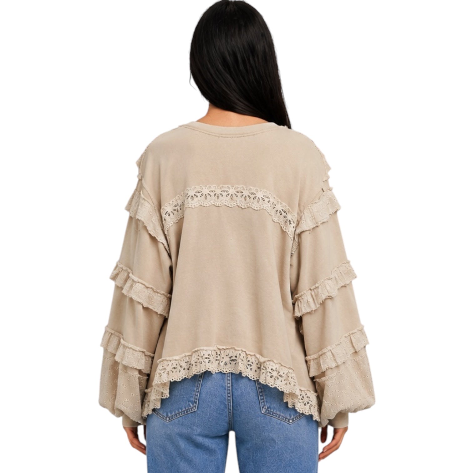 A woman viewed from the back wearing a beige long-sleeve top with layered ruffles and lace trim, paired with blue jeans, against a plain white background.