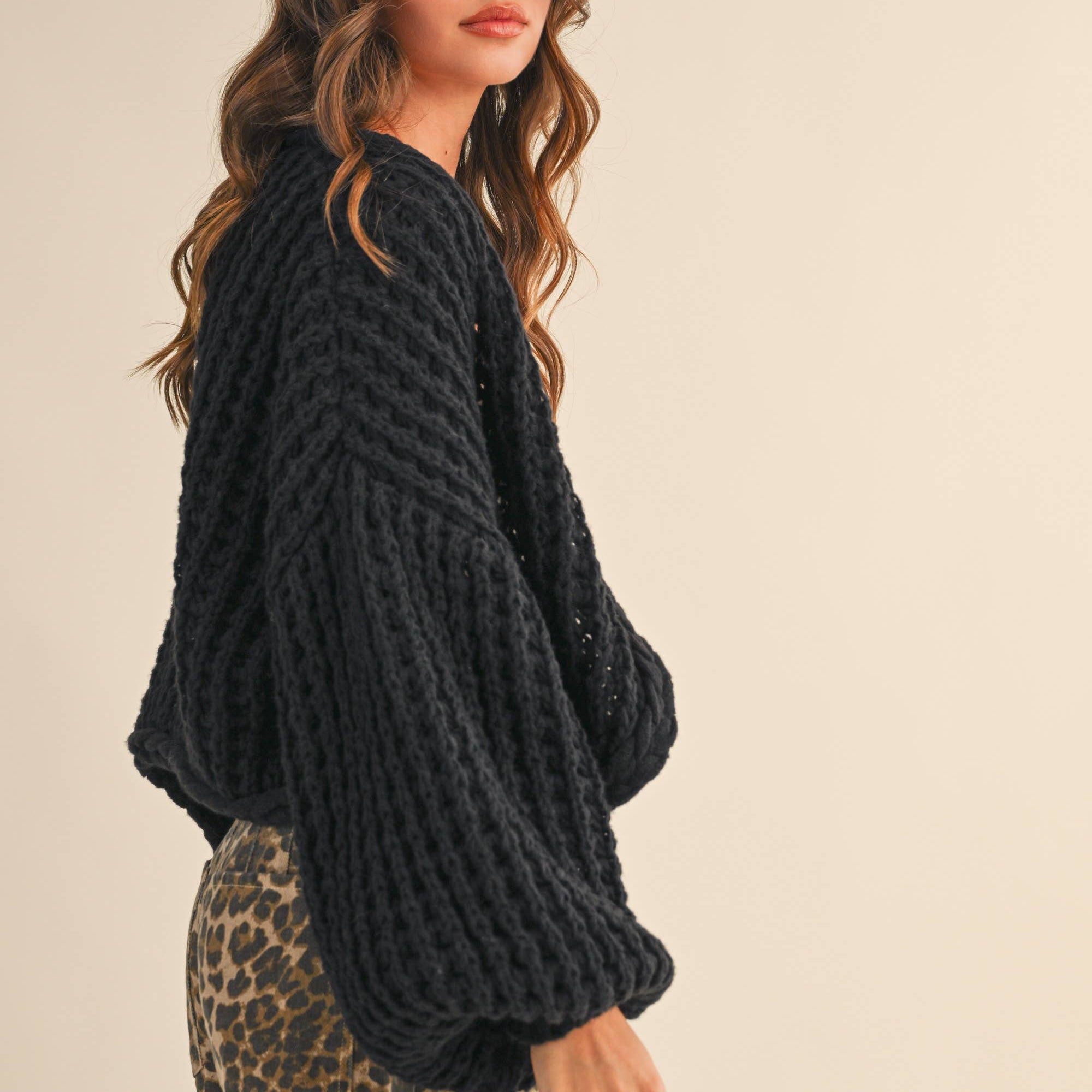 Woman wearing a black knitted sweater on a beige background