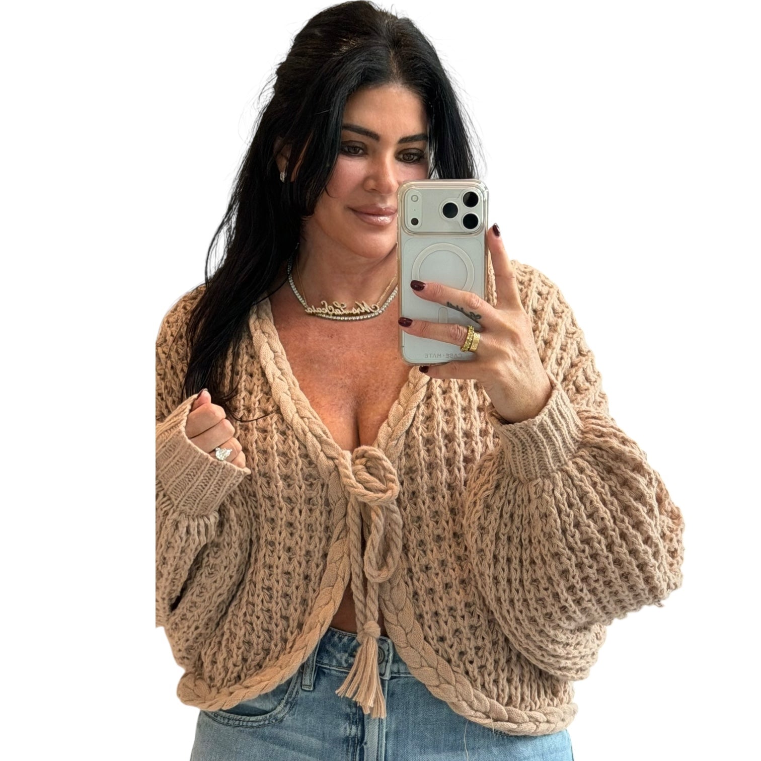 Woman wearing a beige knitted cardigan and taking a selfie on a white background