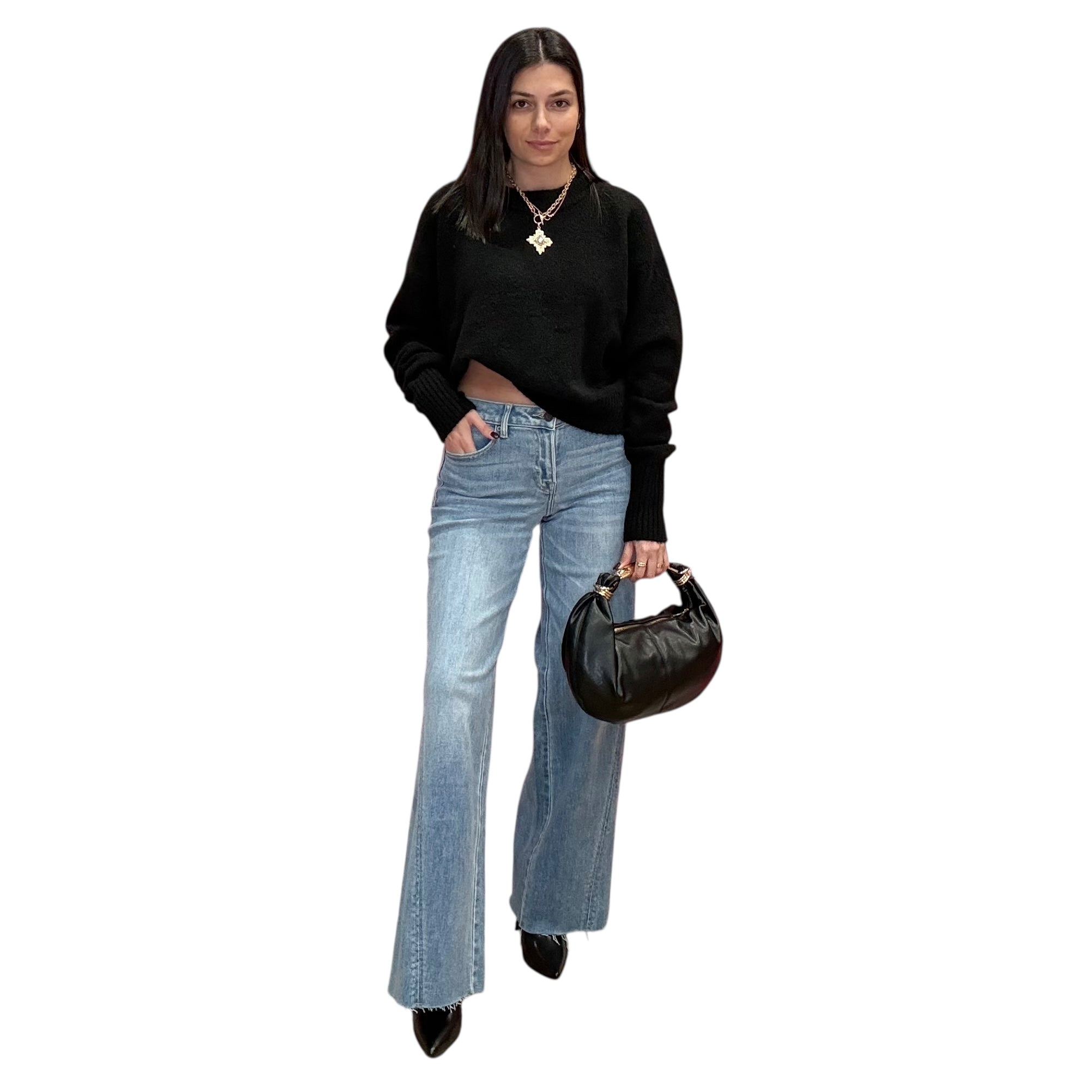 Woman wearing a black sweater and blue jeans holding a black handbag on a white background
