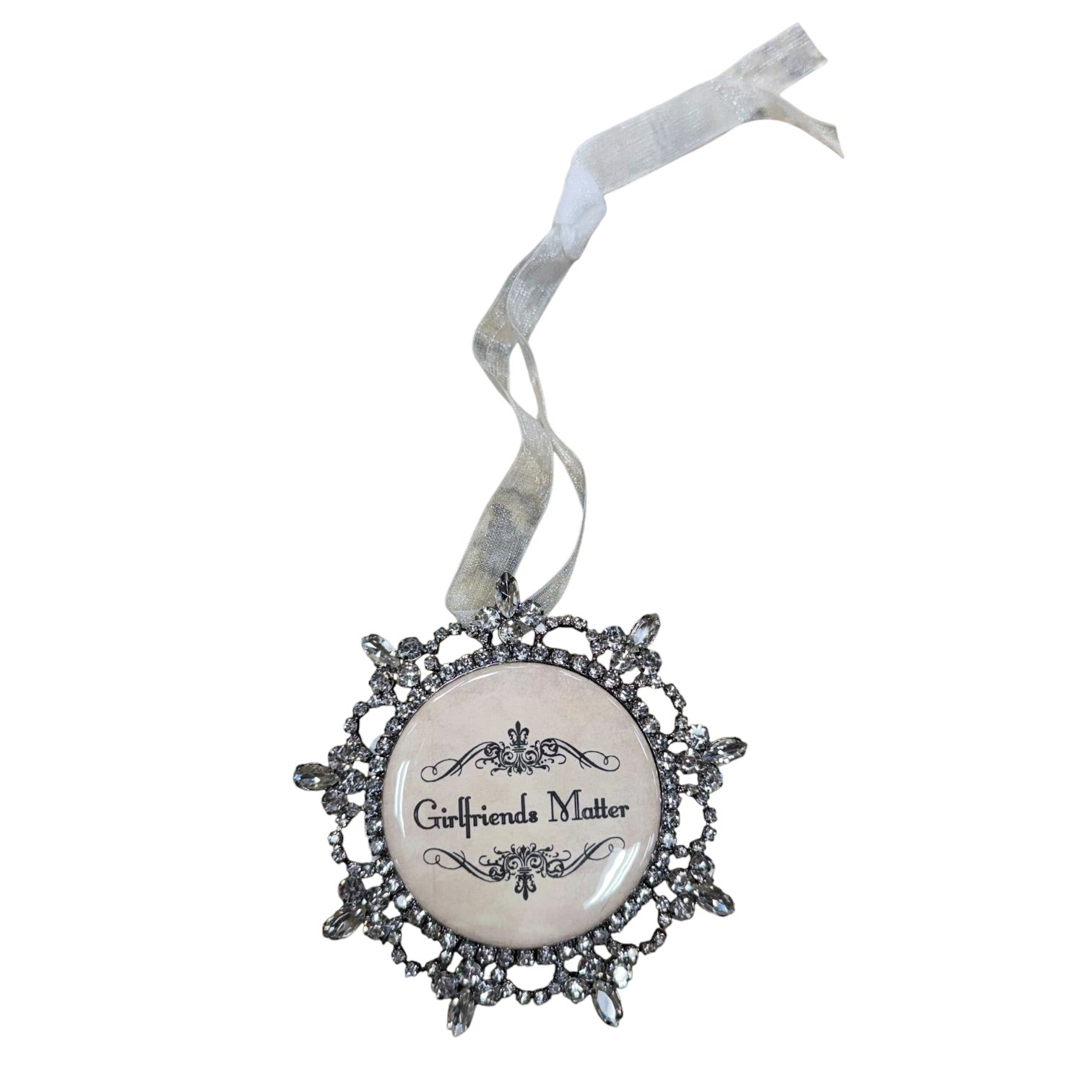 A gothic-style hanging ornament with a round white center featuring the text 'Girlfriends Matter' in black script, surrounded by an ornate silver filigree frame and a white ribbon loop at the top.