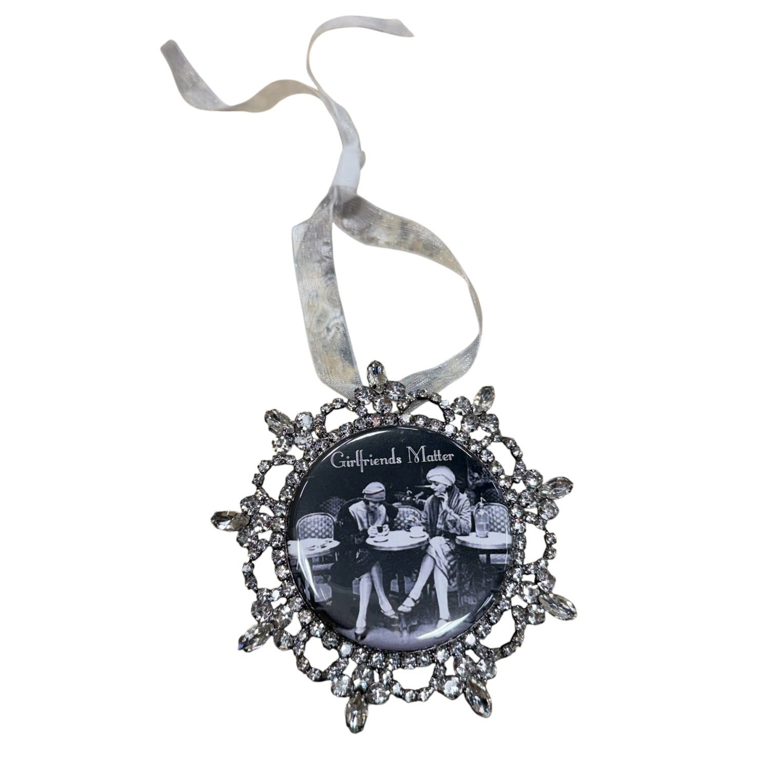 A circular gothic ornament featuring the band 'Cultsdreie Myster' in a black-and-white photo, surrounded by an ornate silver filigree frame with dangling rhinestone-like accents, and hanging from a silver ribbon.