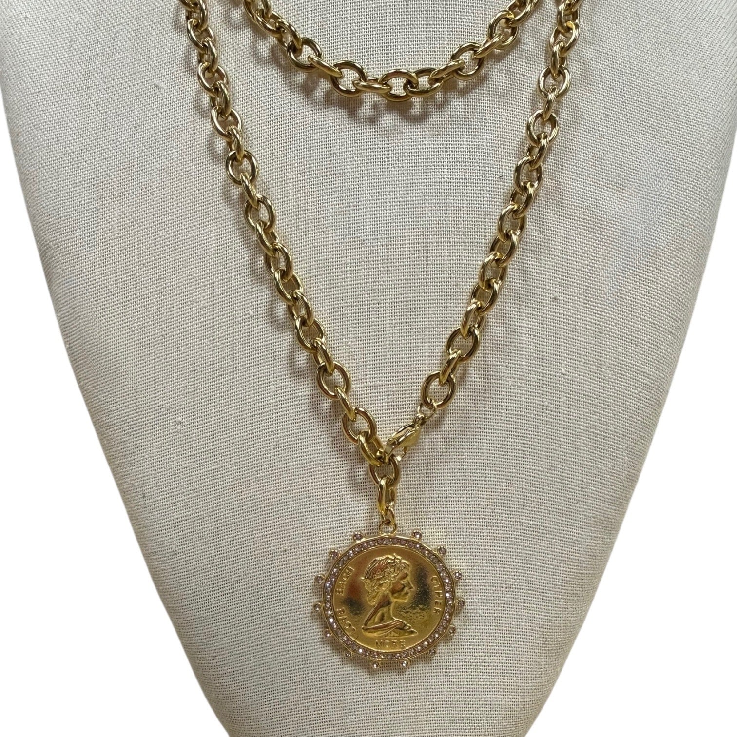 Gold chain necklace with a pendant on a light gray background