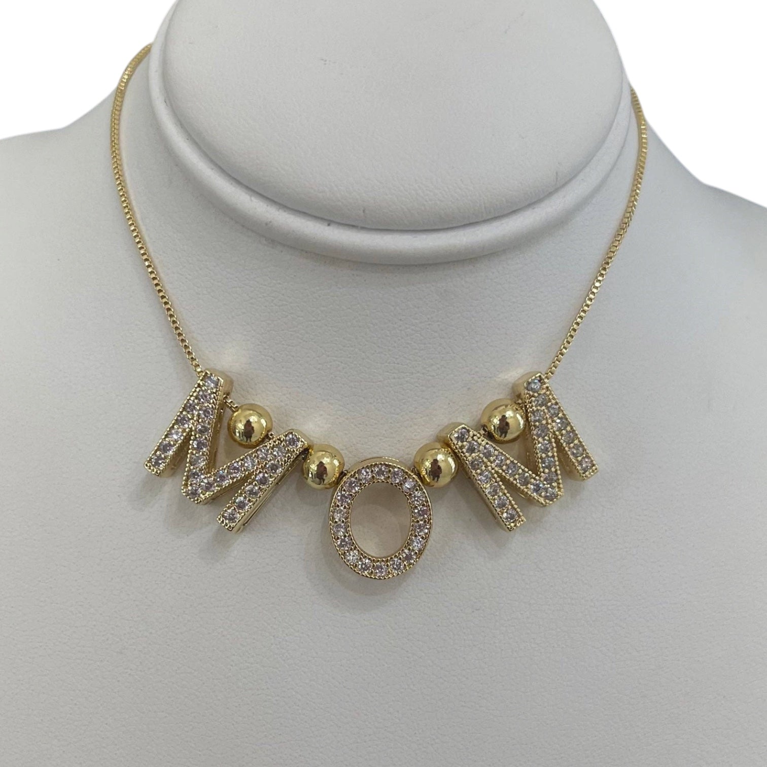 Gold necklace with 'MOM' letters on a mannequin bust
