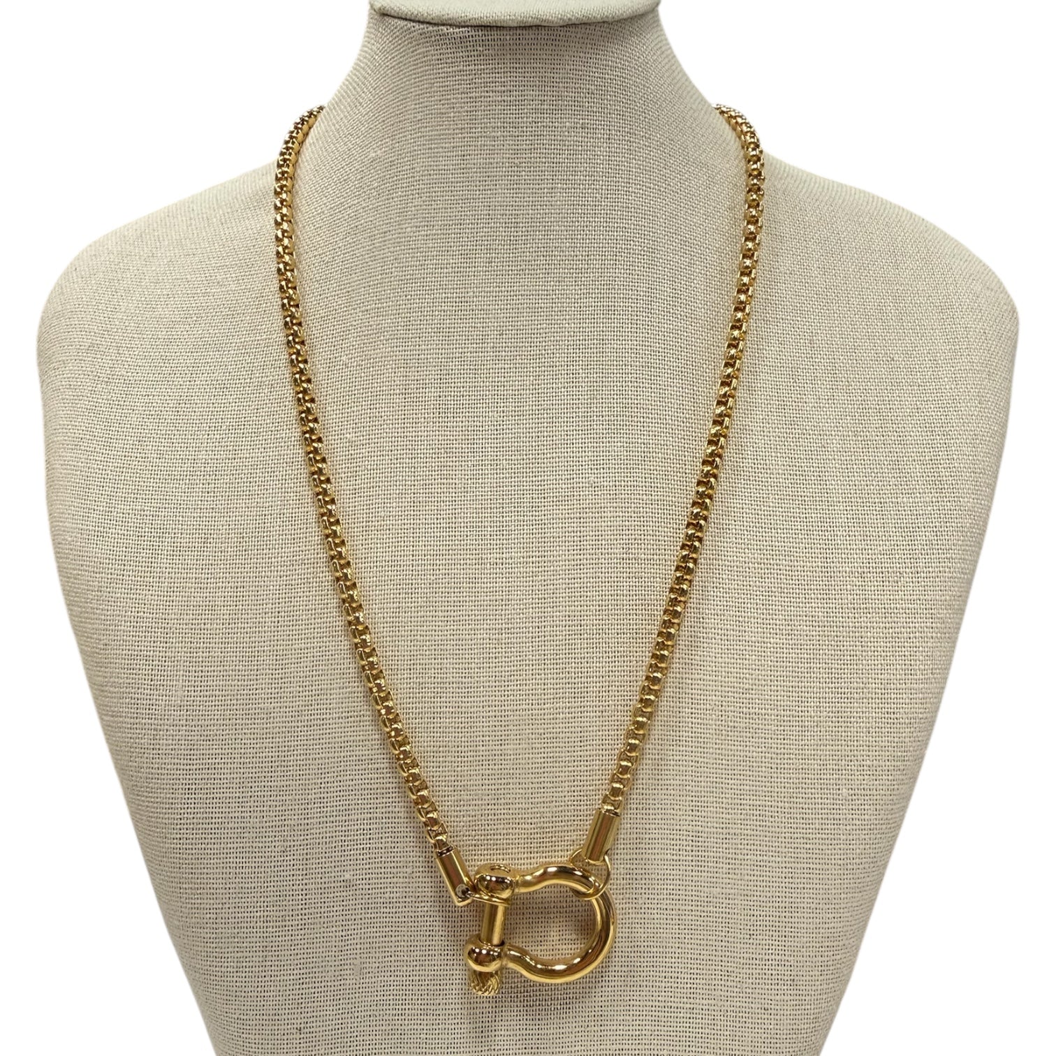 Gold chain necklace on a mannequin bust with a beige background