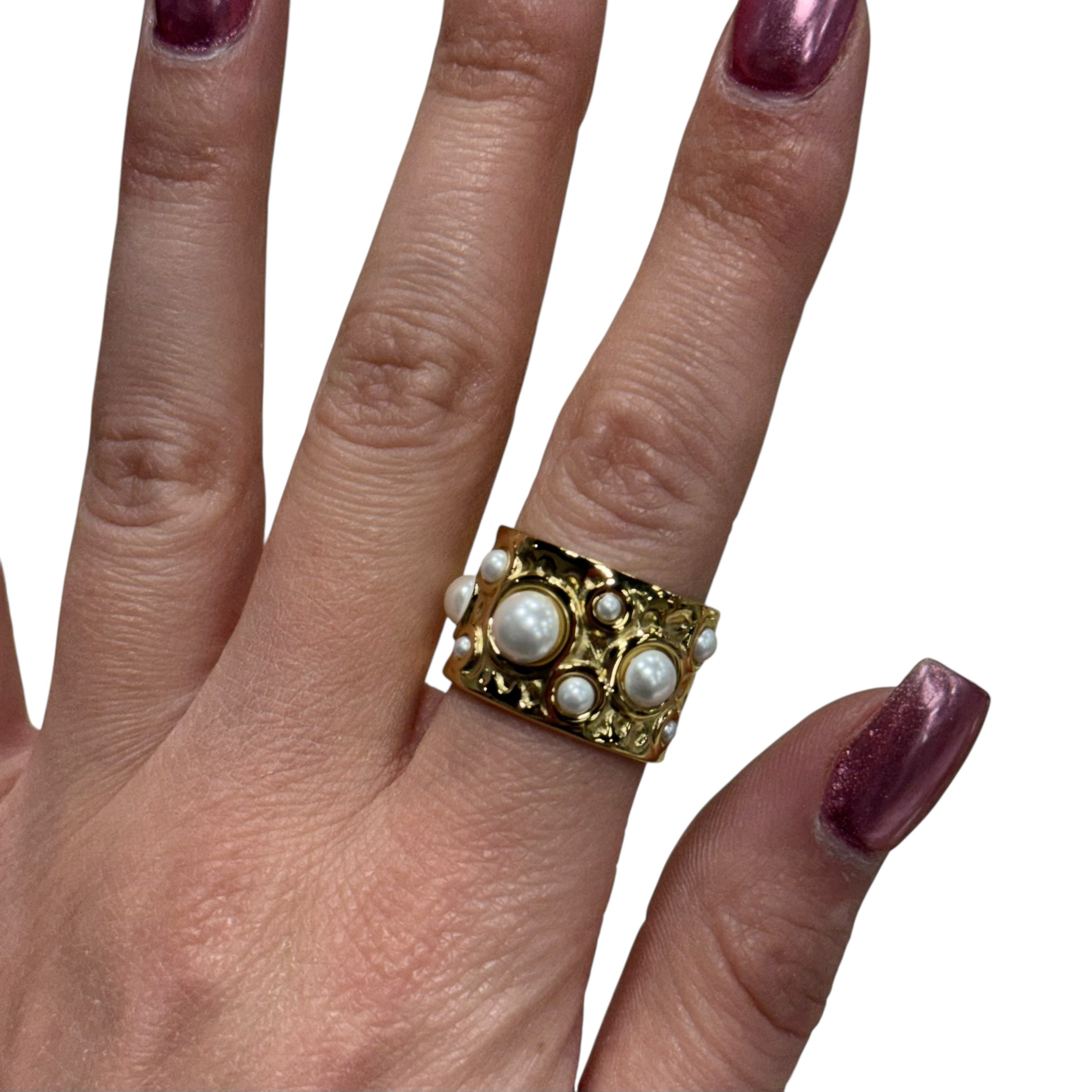 Gold ring with pearls on a finger against a white background