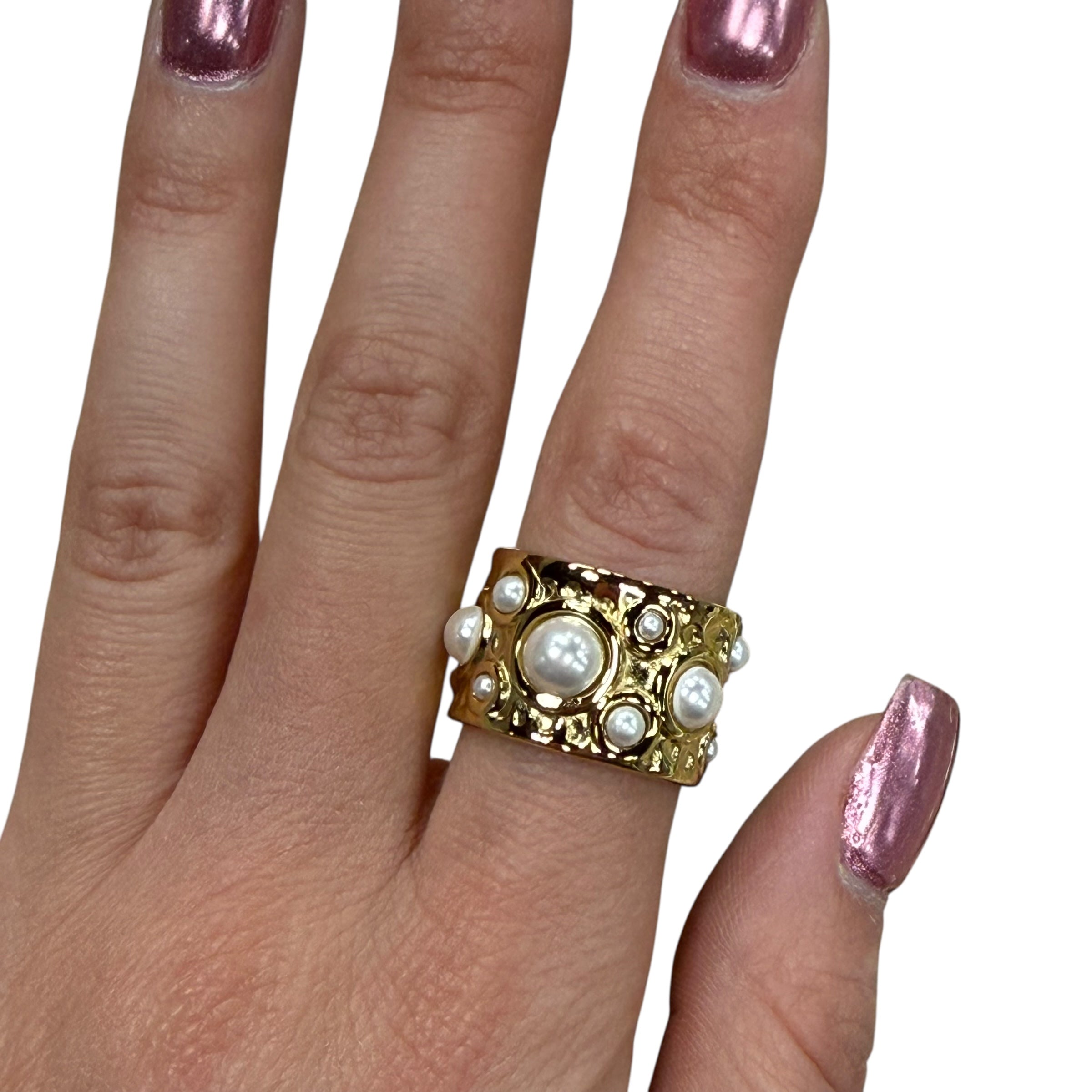 Gold ring with pearls on a hand against a white background