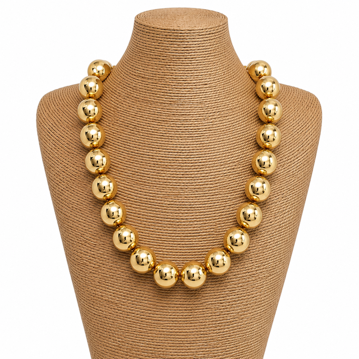 Gold necklace on a brown mannequin bust with a white background