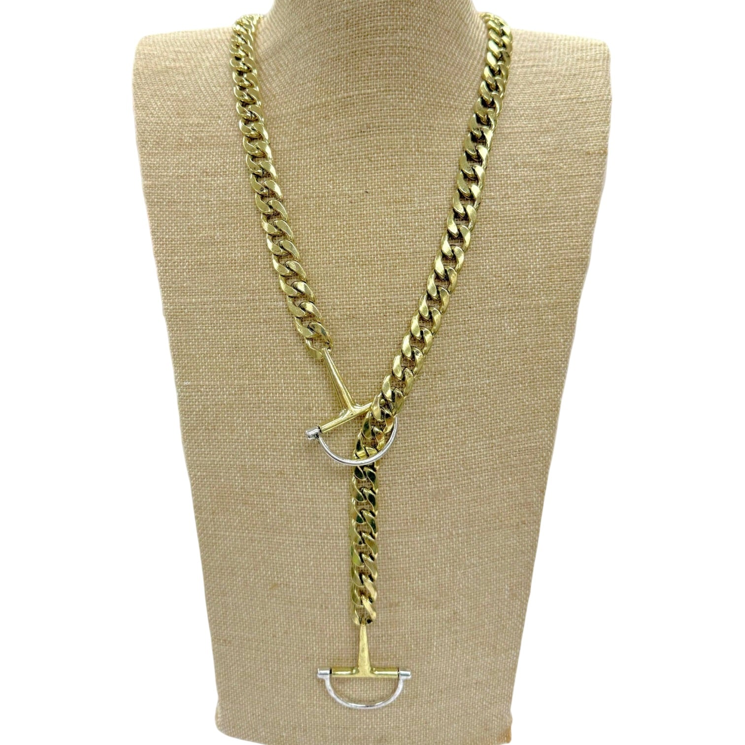 A gold-toned chunky curb chain necklace with a toggle clasp and silver-toned D-ring details, displayed on a beige fabric mannequin bust against a white background.