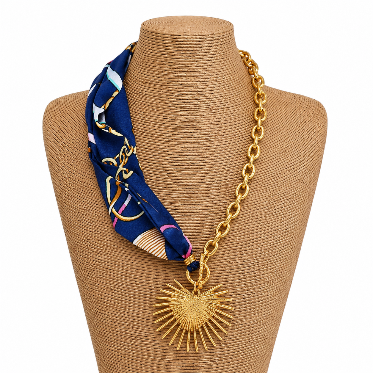 Necklace with a blue patterned fabric wrap and gold chain and heart sunburst charm on a white background