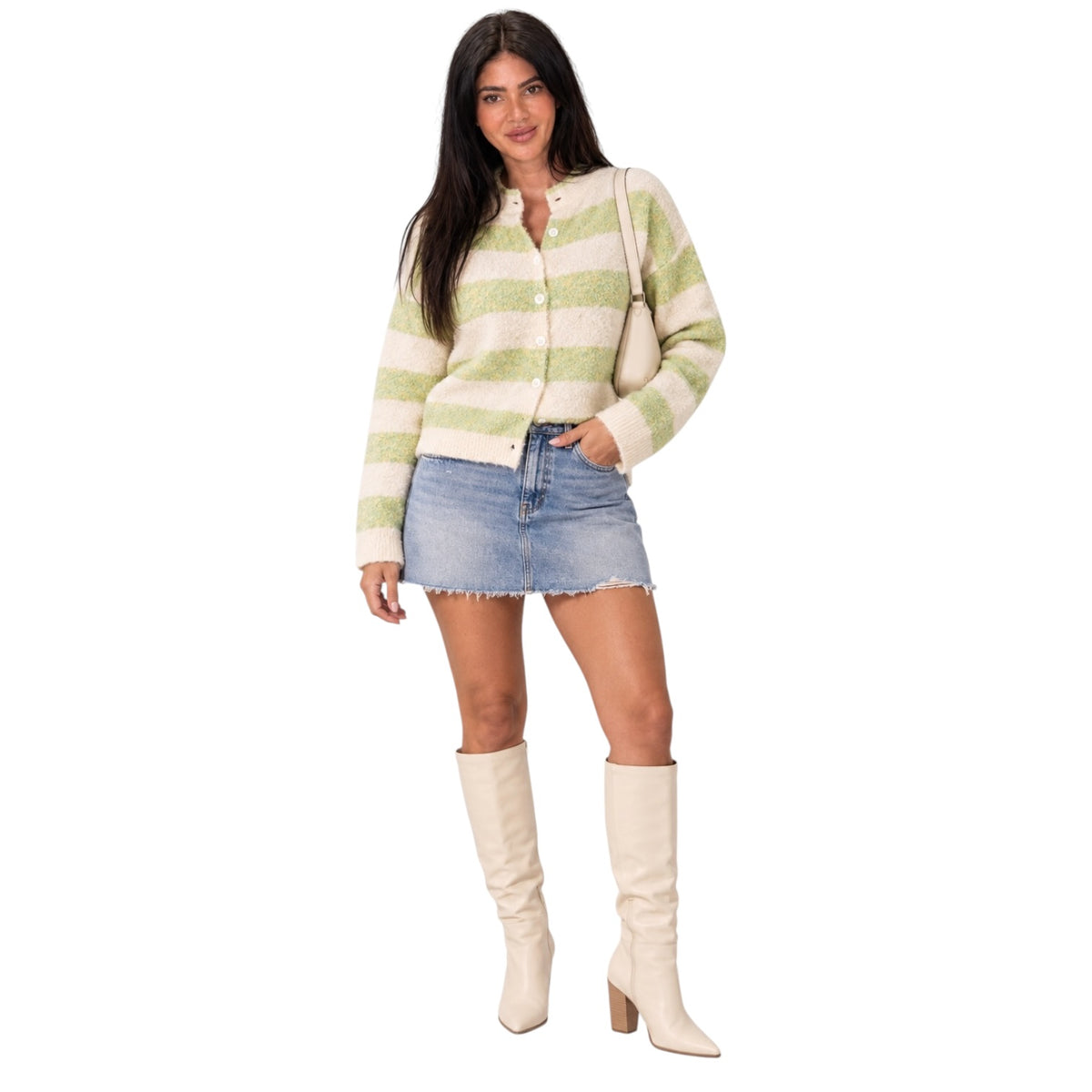 A woman modeling a cream and light green striped knit cardigan, paired with a denim mini skirt and cream knee-high boots, against a solid white background.