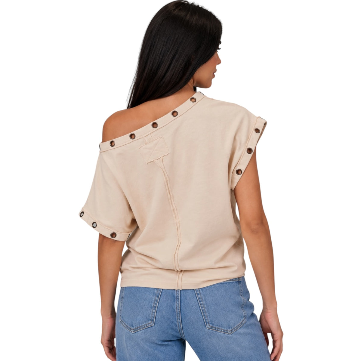 A woman shown from the back wearing a beige off-the-shoulder top with decorative brown buttons along the neckline and sleeve edges, paired with blue jeans, against a plain white background.