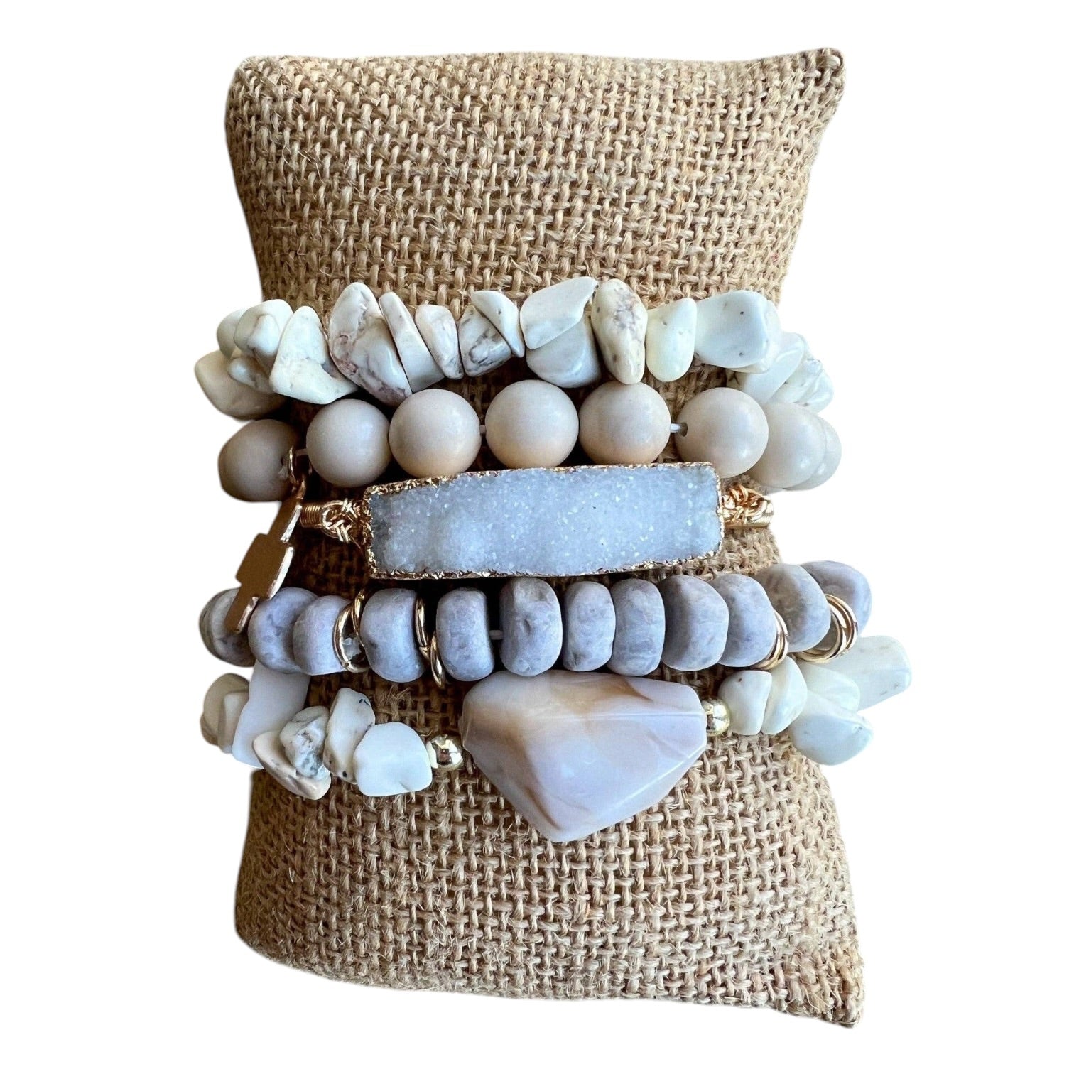 Stack of stone and shell bracelets on a burlap surface
