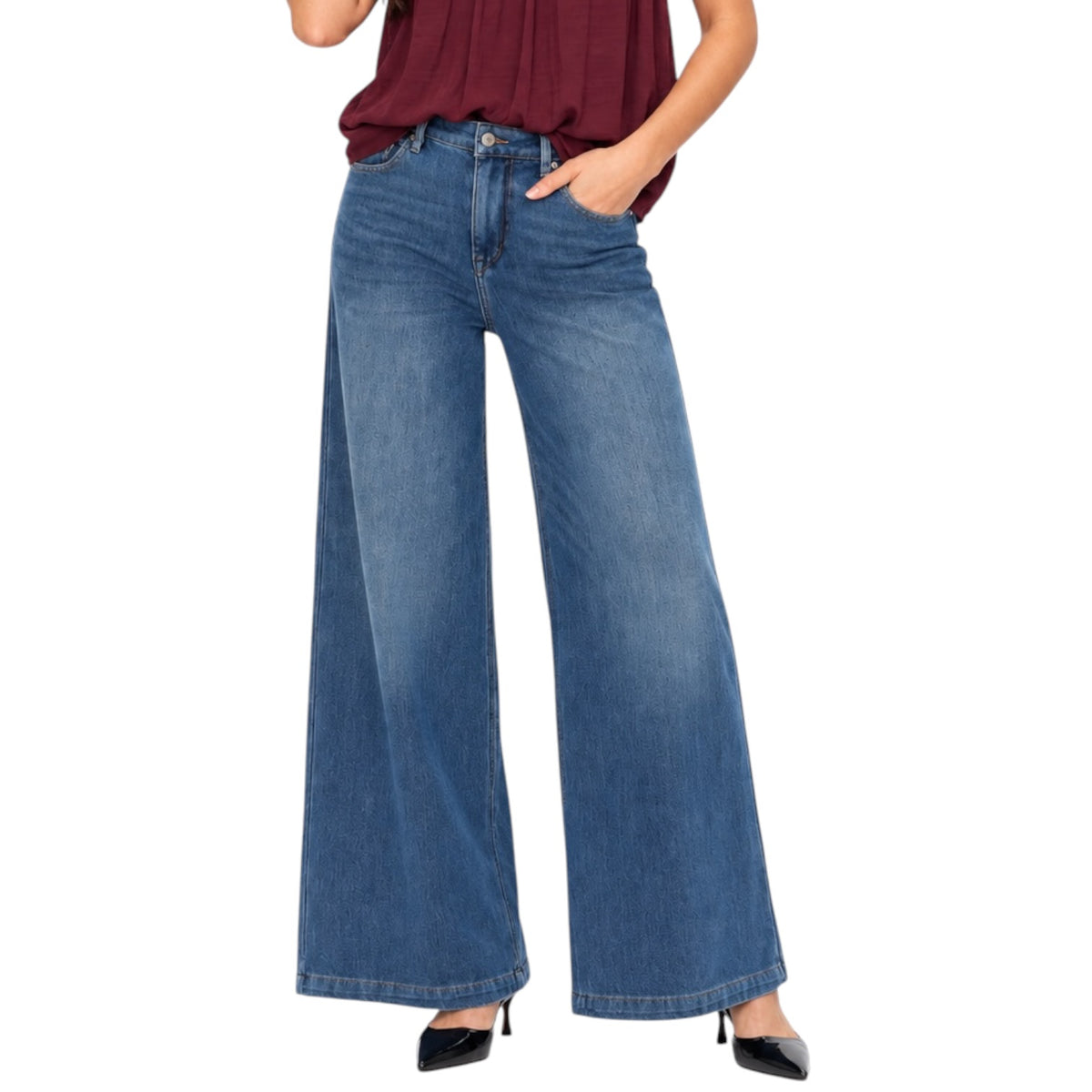 A model wearing a pair of wide-leg blue denim jeans with a faded wash, paired with a dark red top and black heels, shown against a plain white background.