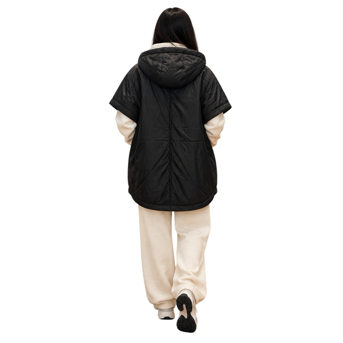 A person shown from the back wearing a black hooded puffer jacket with cream-colored sleeves and cream pants, walking against a plain white background.